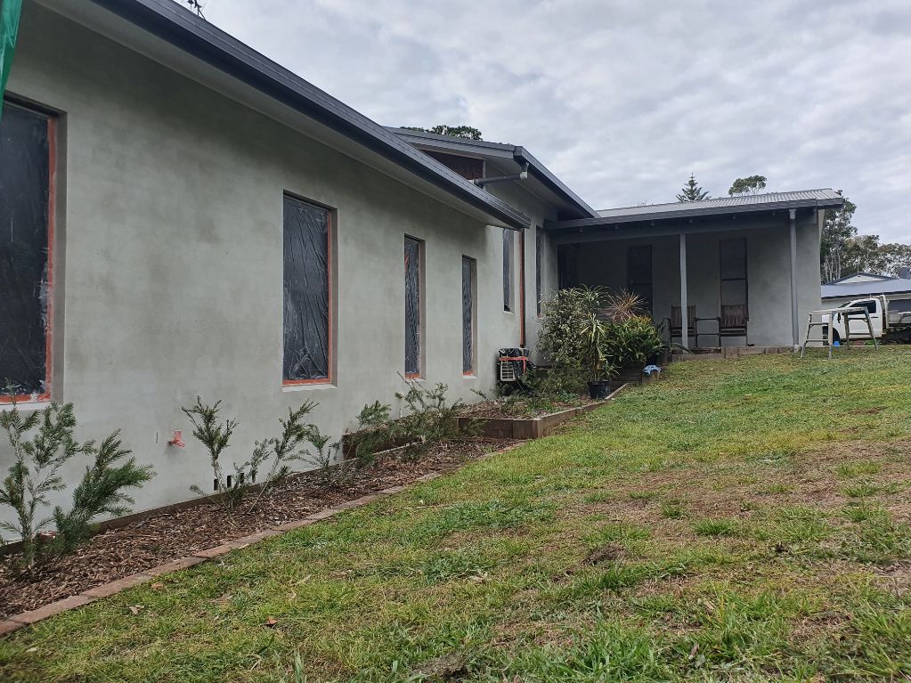 A House With a Lot of Windows is Sitting on Top of a Lush Green Field — Brett Rayner Cement Rendering In Goonellabah, NSW
