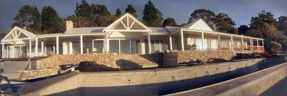 A Large White House is Sitting on Top of a Hill — Brett Rayner Cement Rendering In Goonellabah, NSW