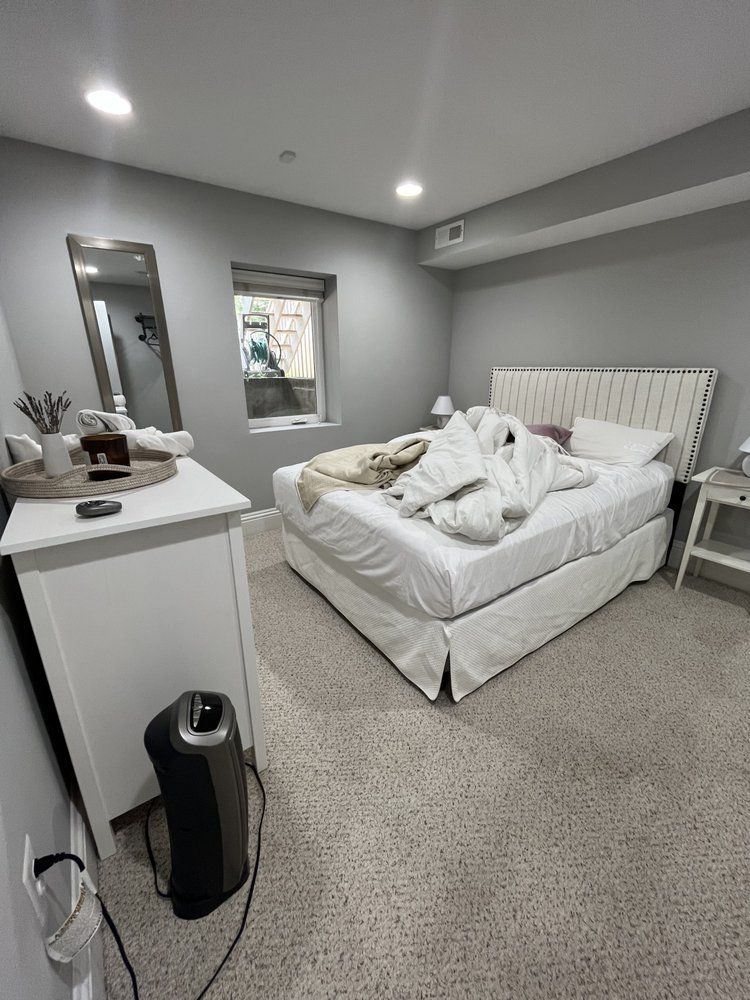 A bedroom with a bed , dresser , nightstand and mirror.