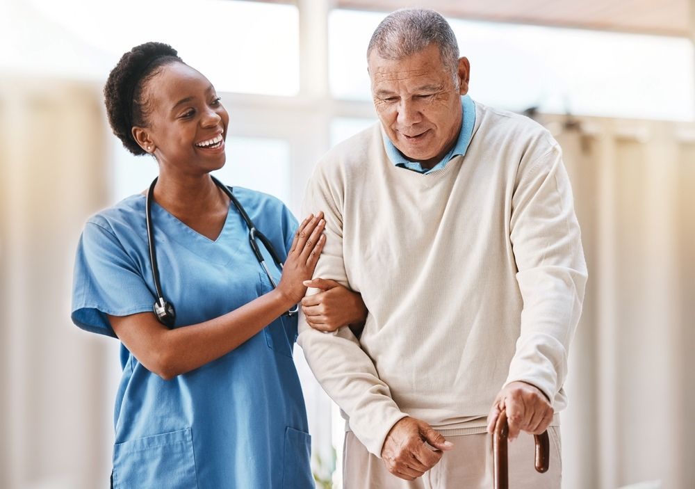 A Nurse Is Helping An Elderly Man Walk With A Cane