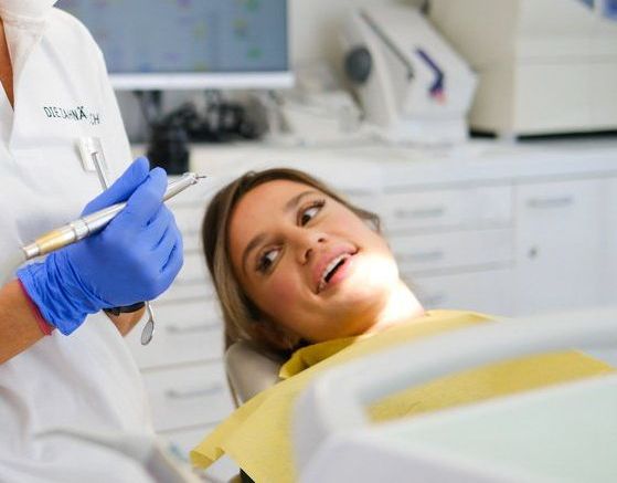 A woman is sitting in a dental chair getting her teeth examined by a dentist.