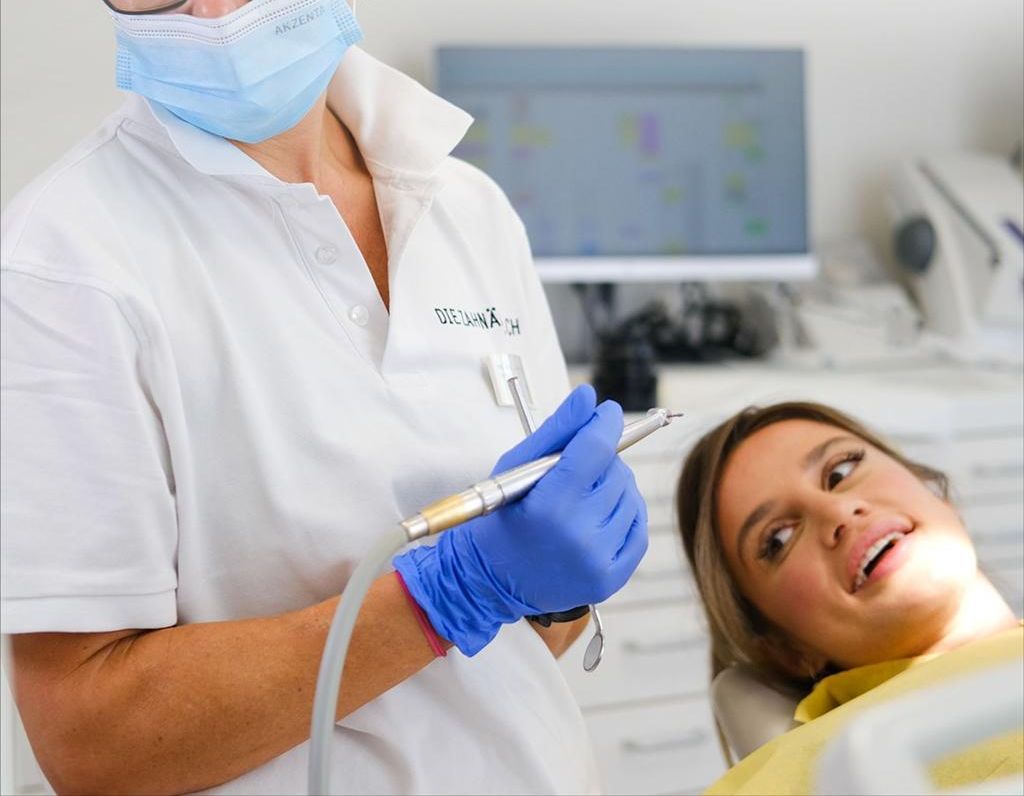 A dentist is examining a woman 's teeth in a dental chair.