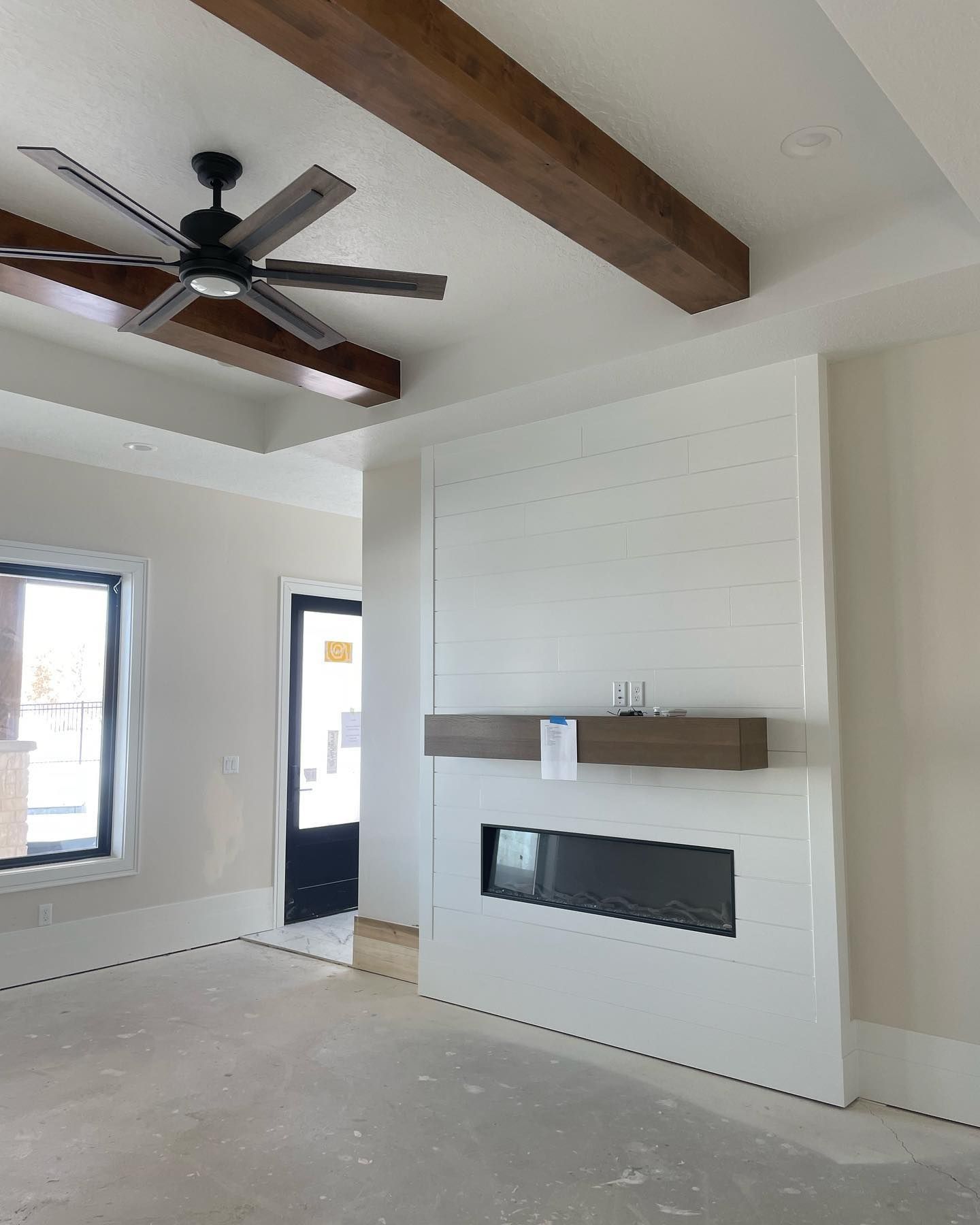 Living room with white fireplace, wooden beams, and a ceiling fan.