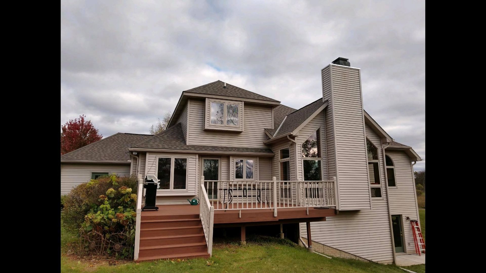 A large white house with a large deck and stairs.