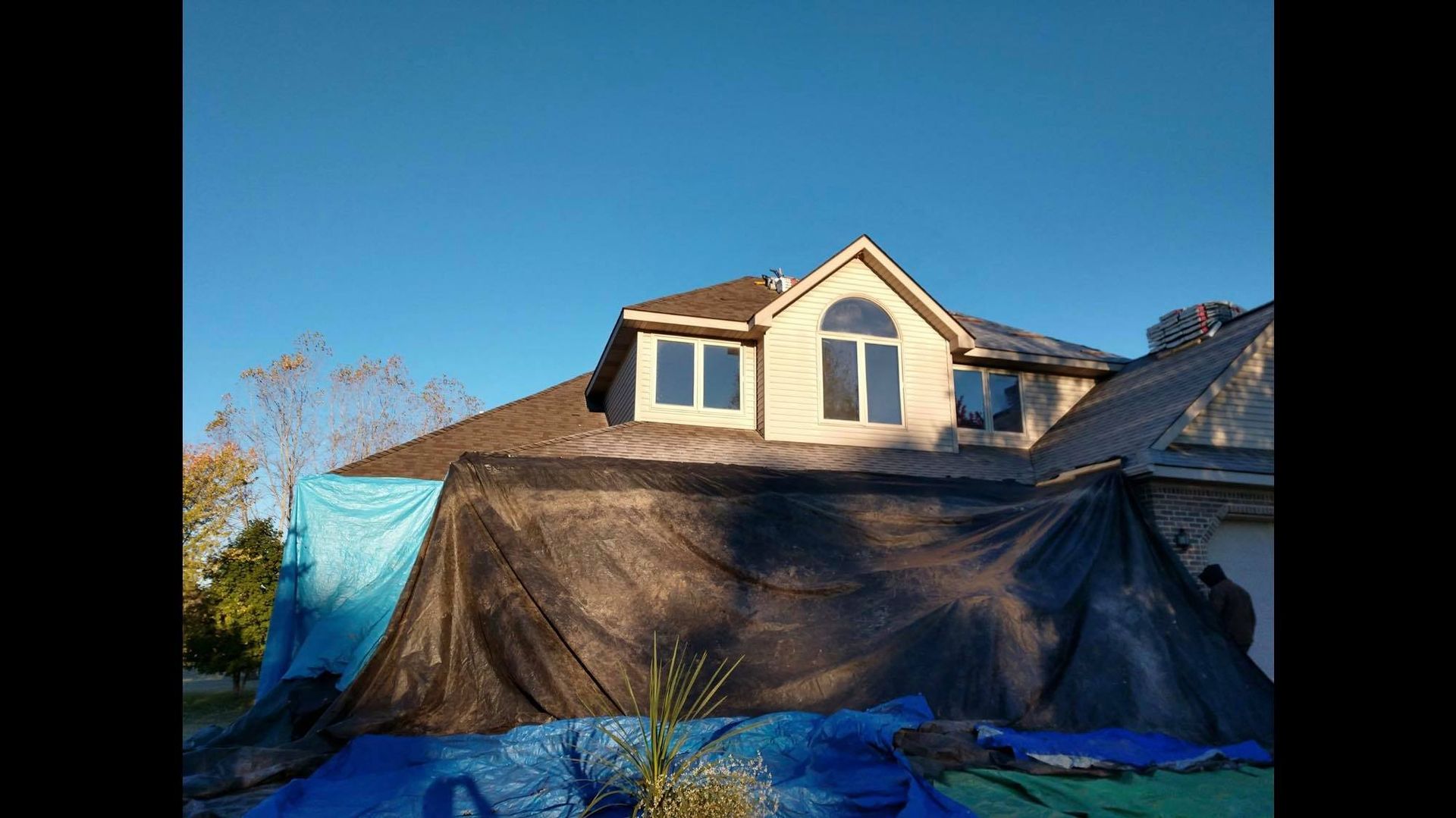 A large house is covered in a blue tarp.