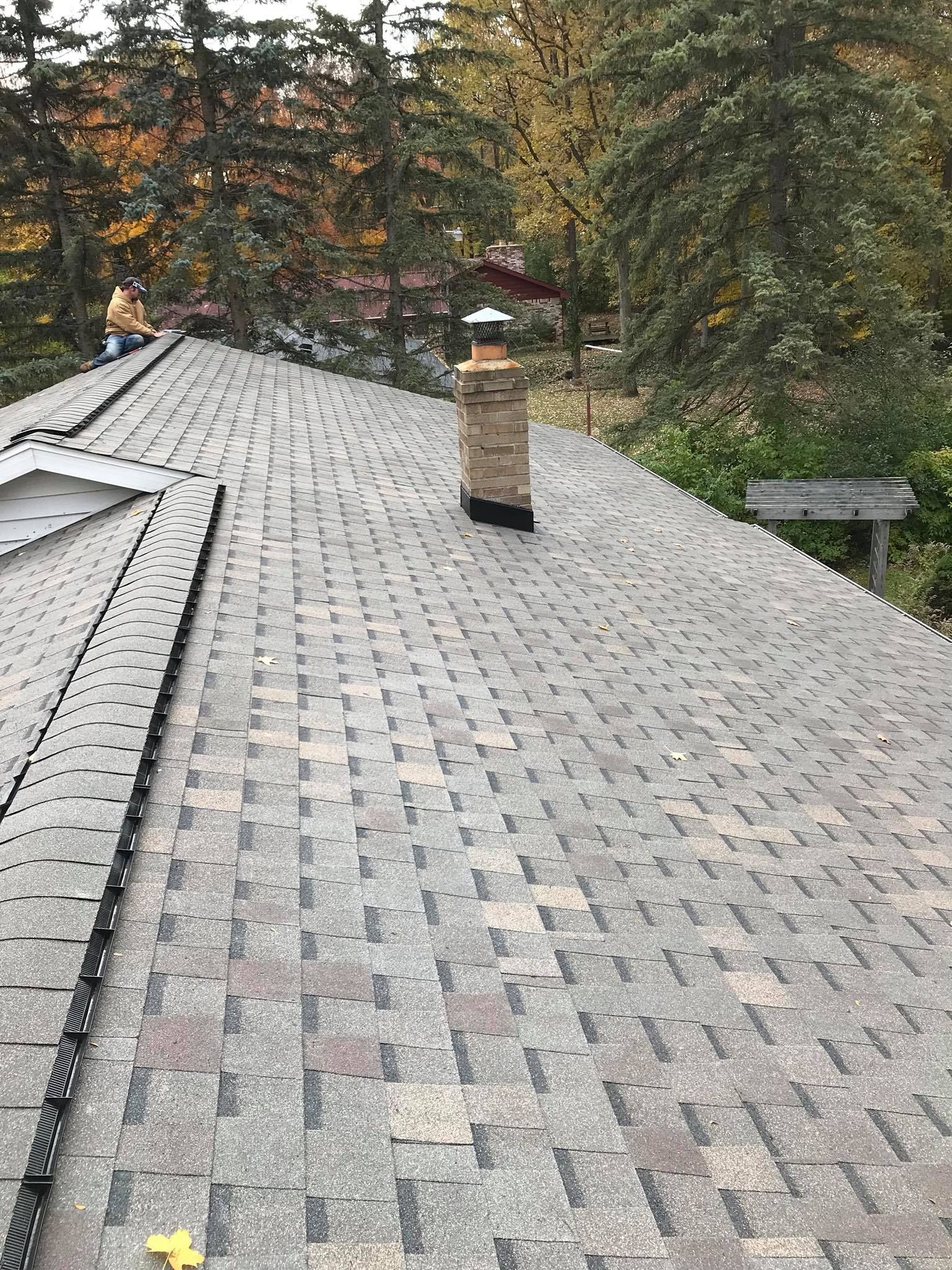 A roof with a chimney on it and trees in the background.