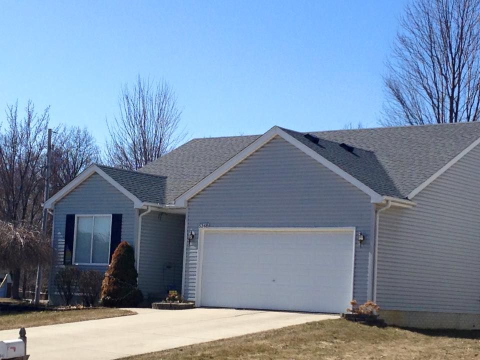 A house with a white garage door and a blue sky in the background