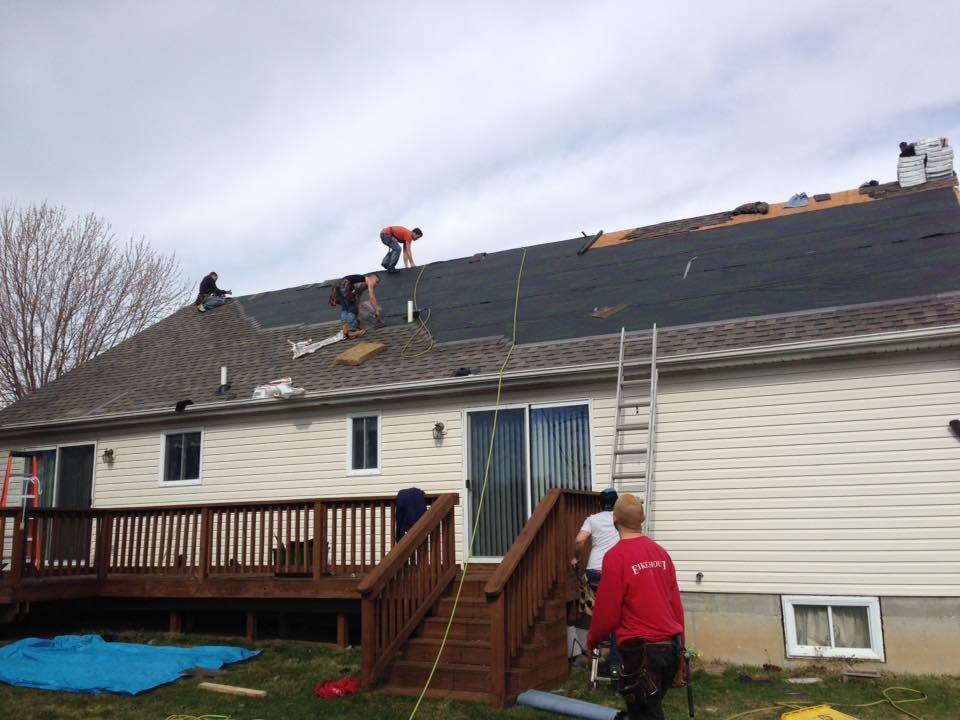A group of men are working on the roof of a house.