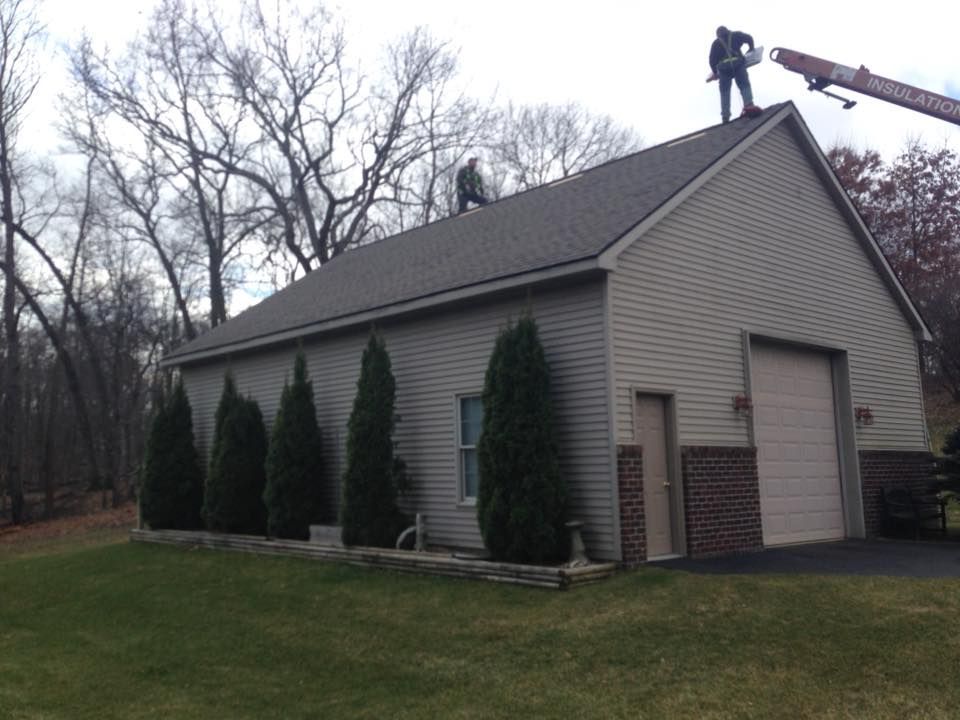 Two men are working on the roof of a garage