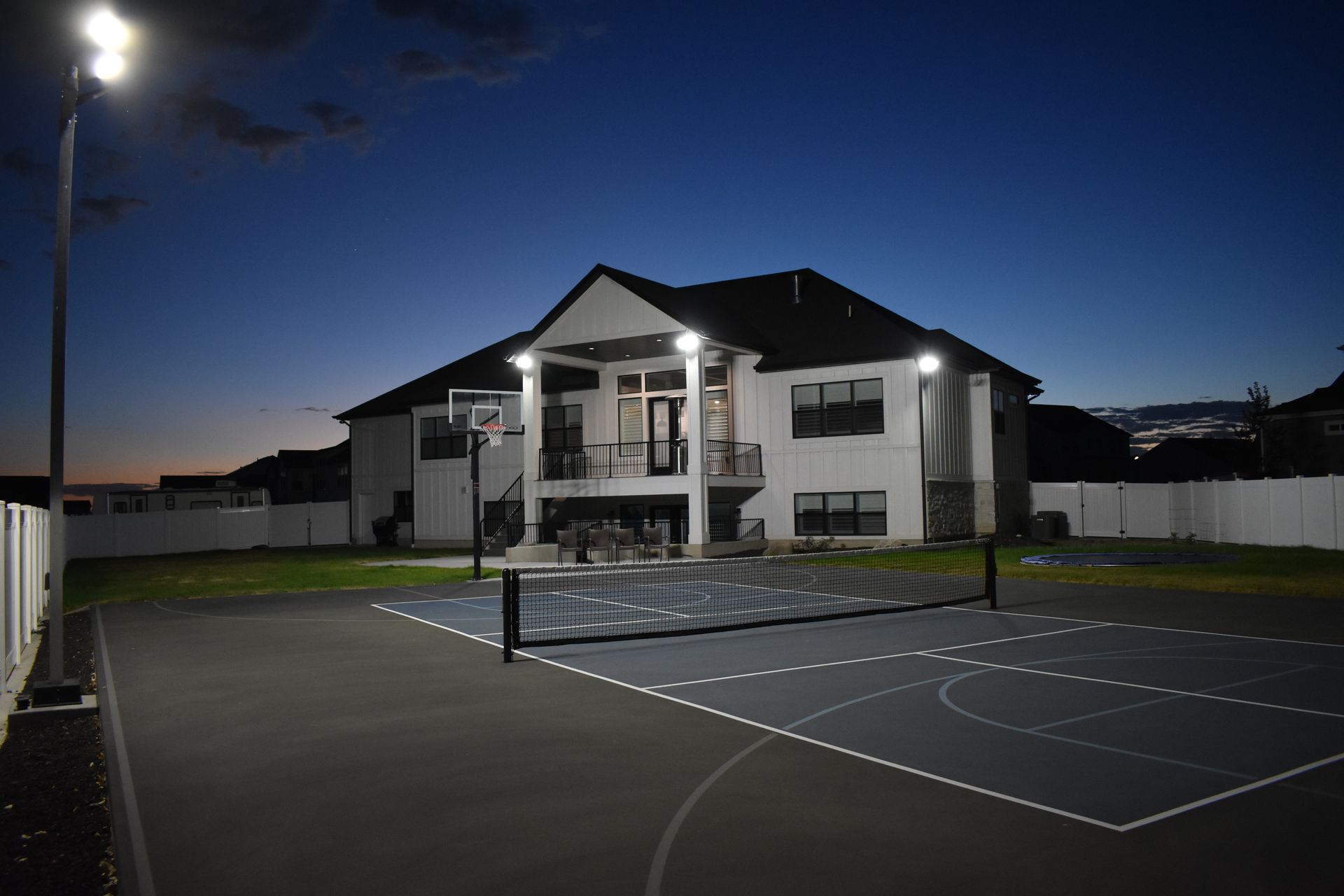 night shot of house and pickleball court in the backyard