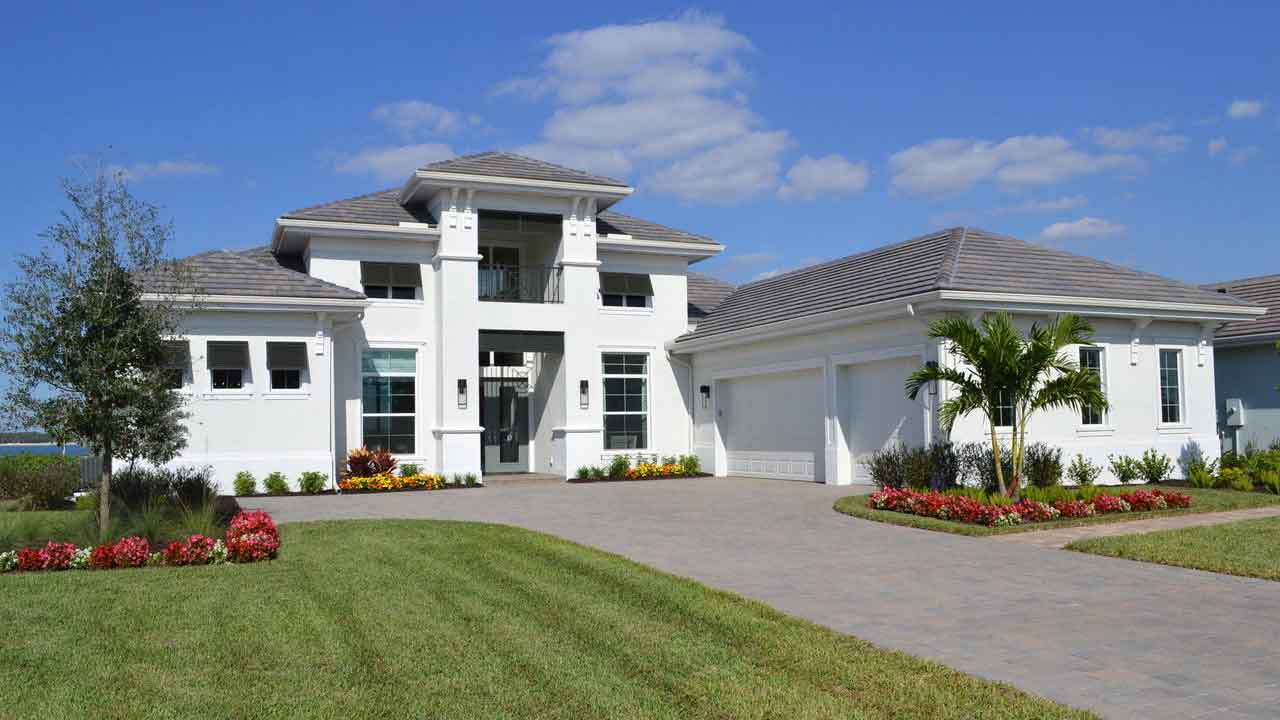 A large white house with a lush green lawn in front of it.