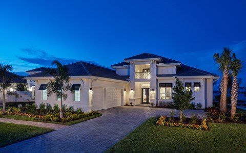 A large white house with palm trees in front of it at night.