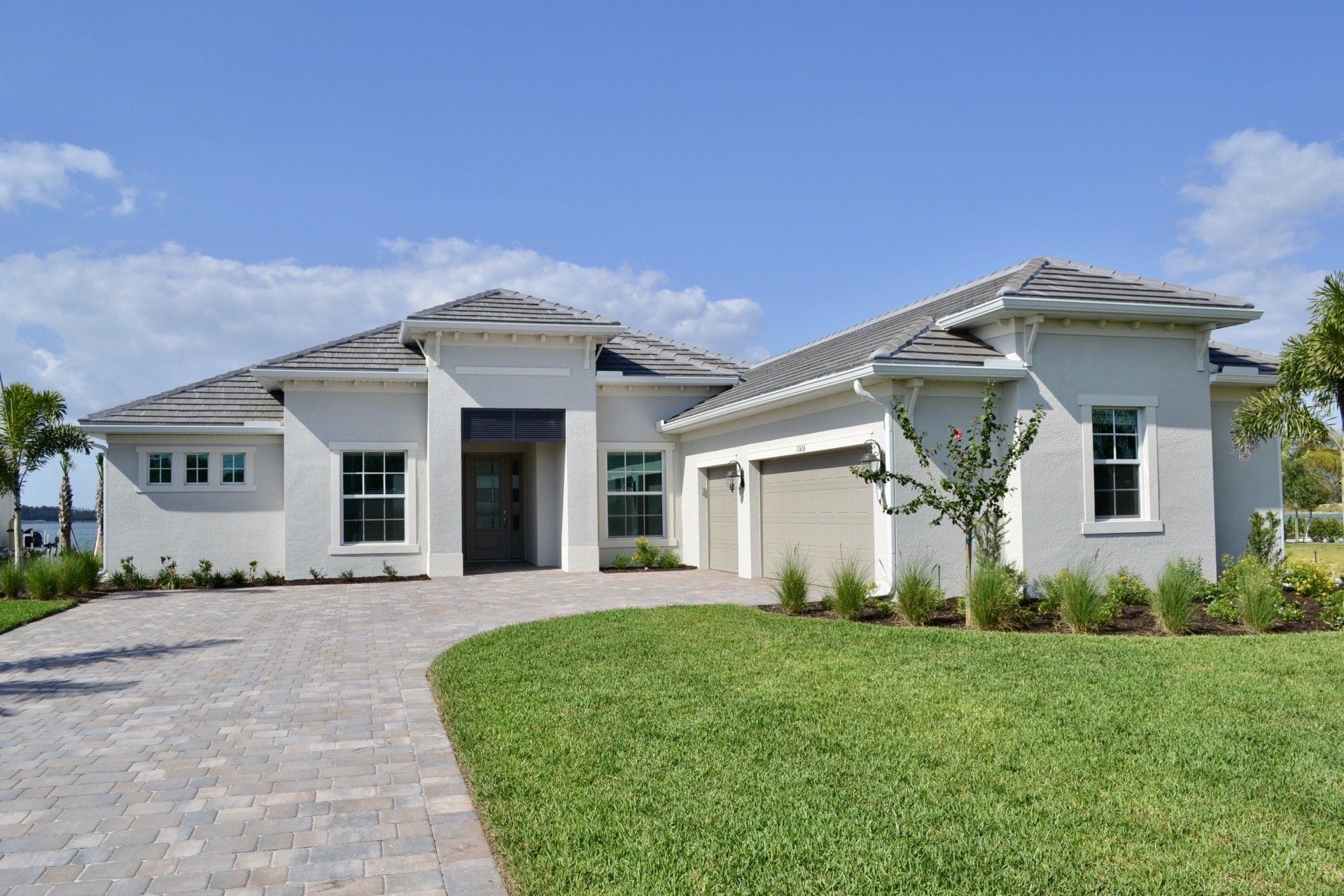 A white house with a gray roof is sitting on top of a lush green lawn.