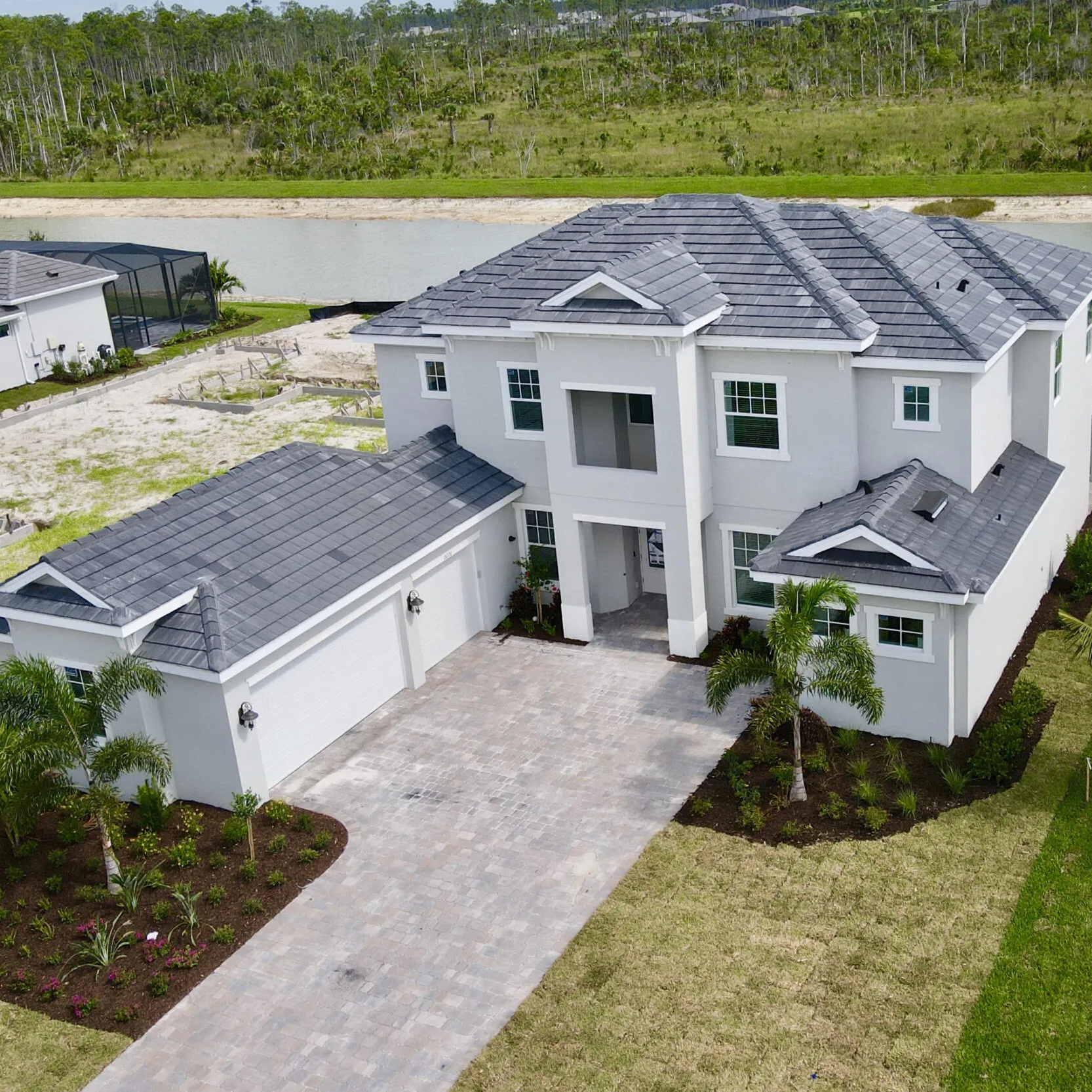 An aerial view of a large white house with a gray roof