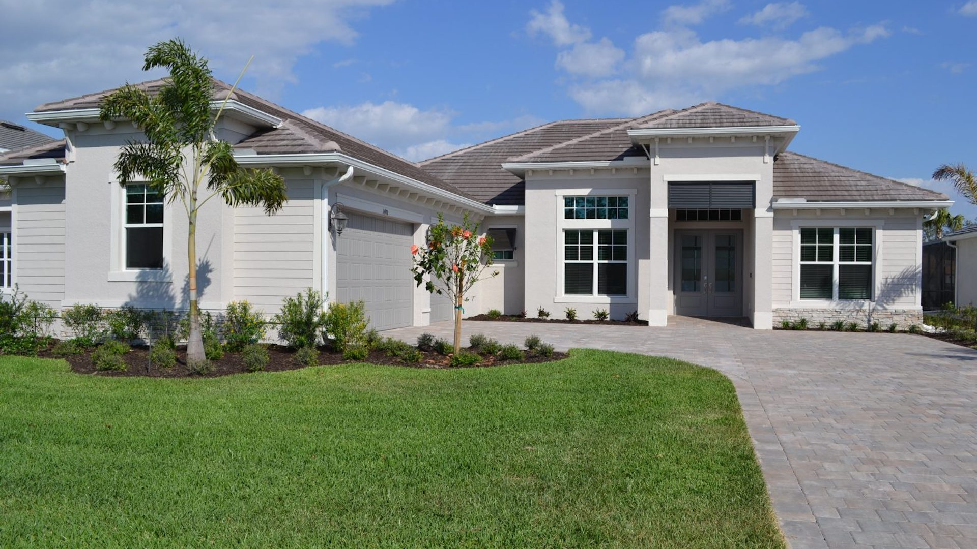 A large white house with a brown roof is sitting on top of a lush green lawn.