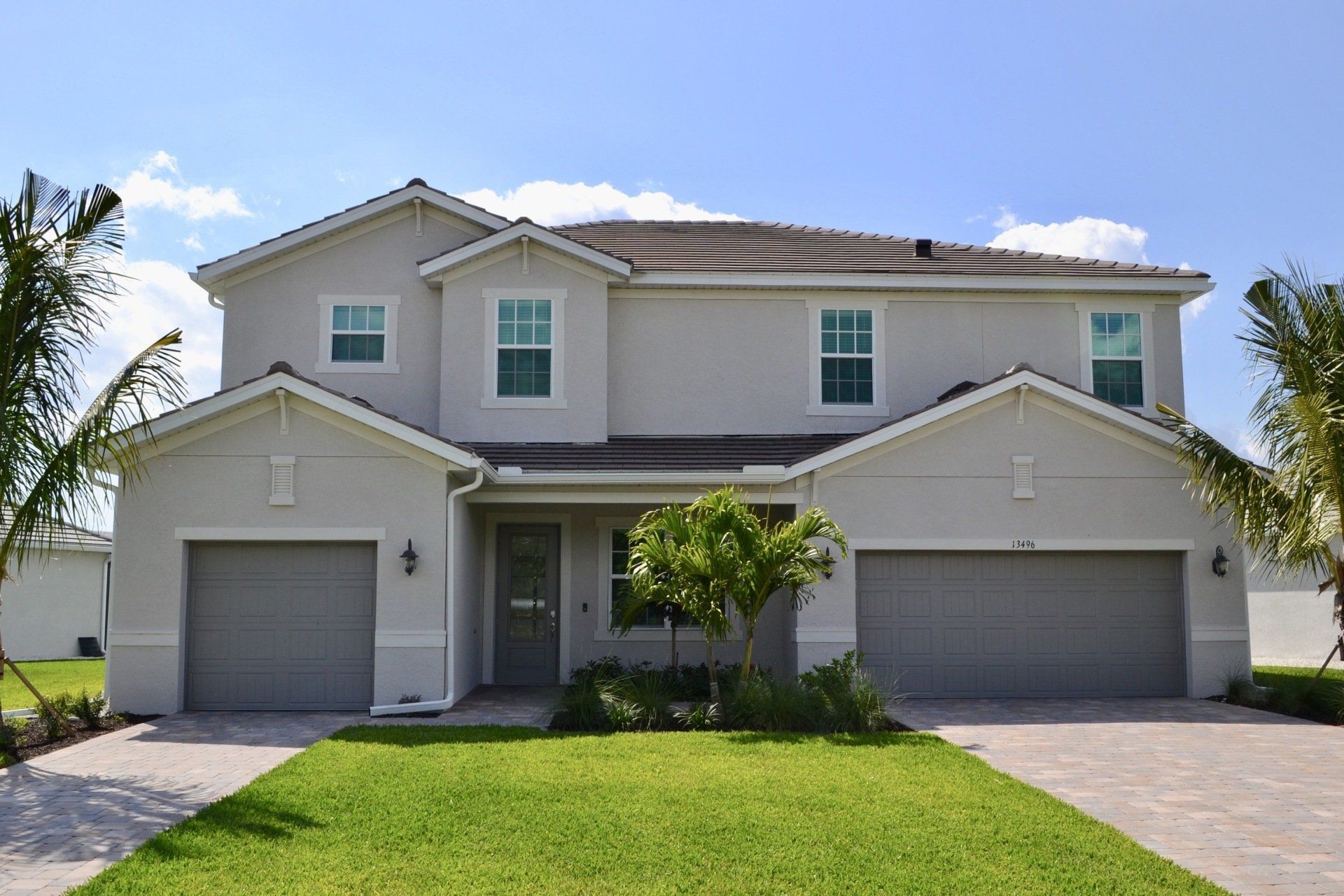 A large house with two garages and a lush green lawn