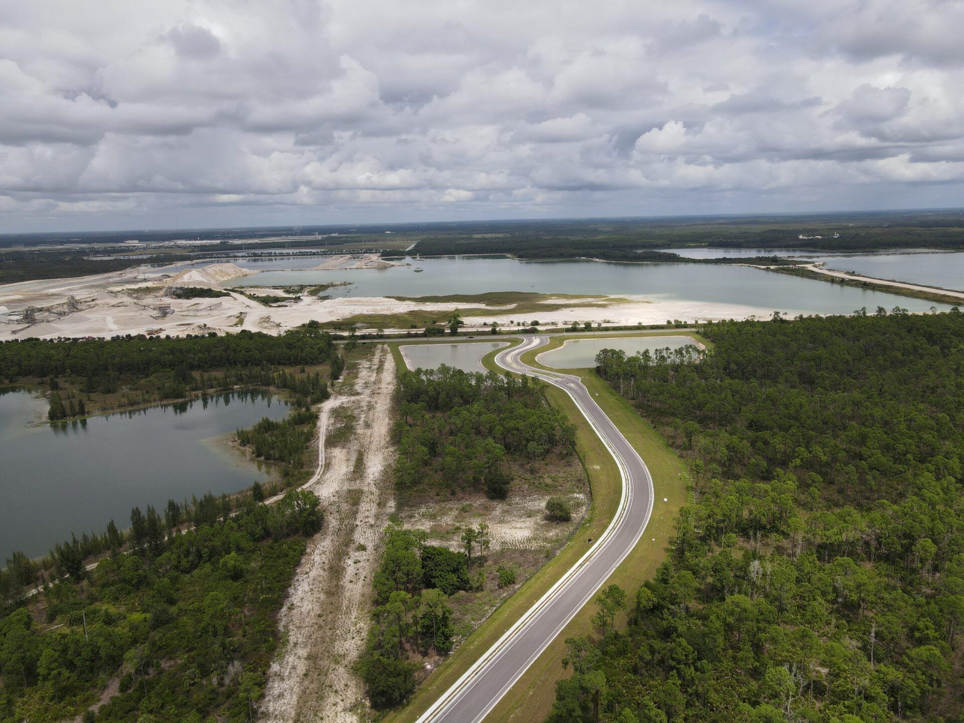 An aerial view of a road surrounded by trees and lakes