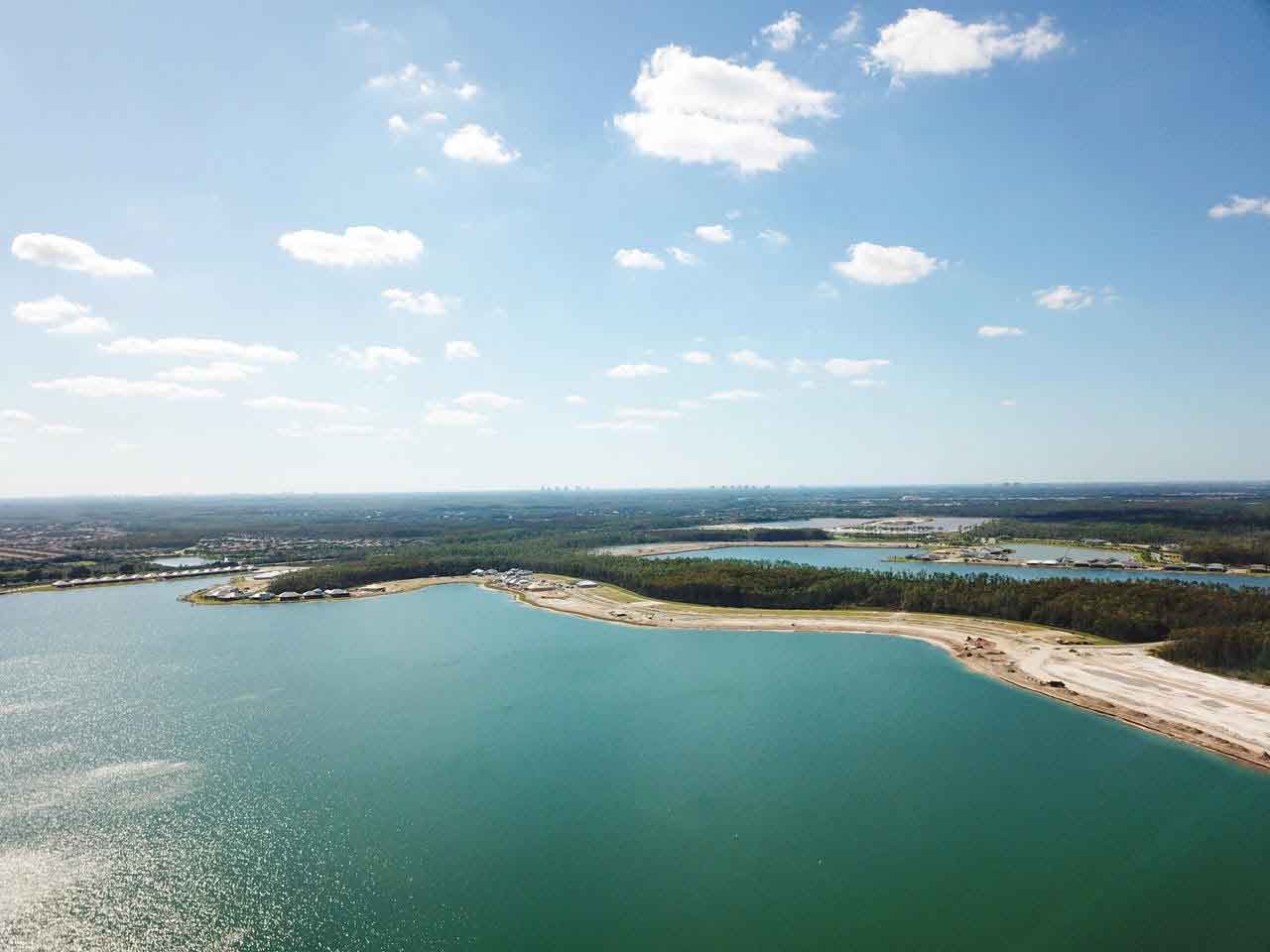 An aerial view of a large body of water surrounded by trees on a sunny day.