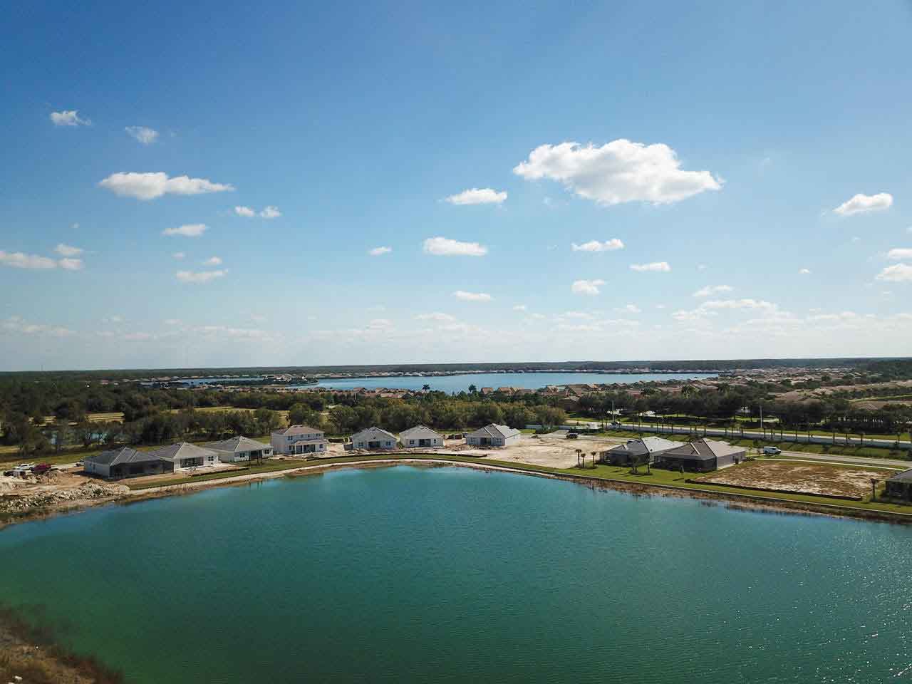 An aerial view of a lake with houses in the background.