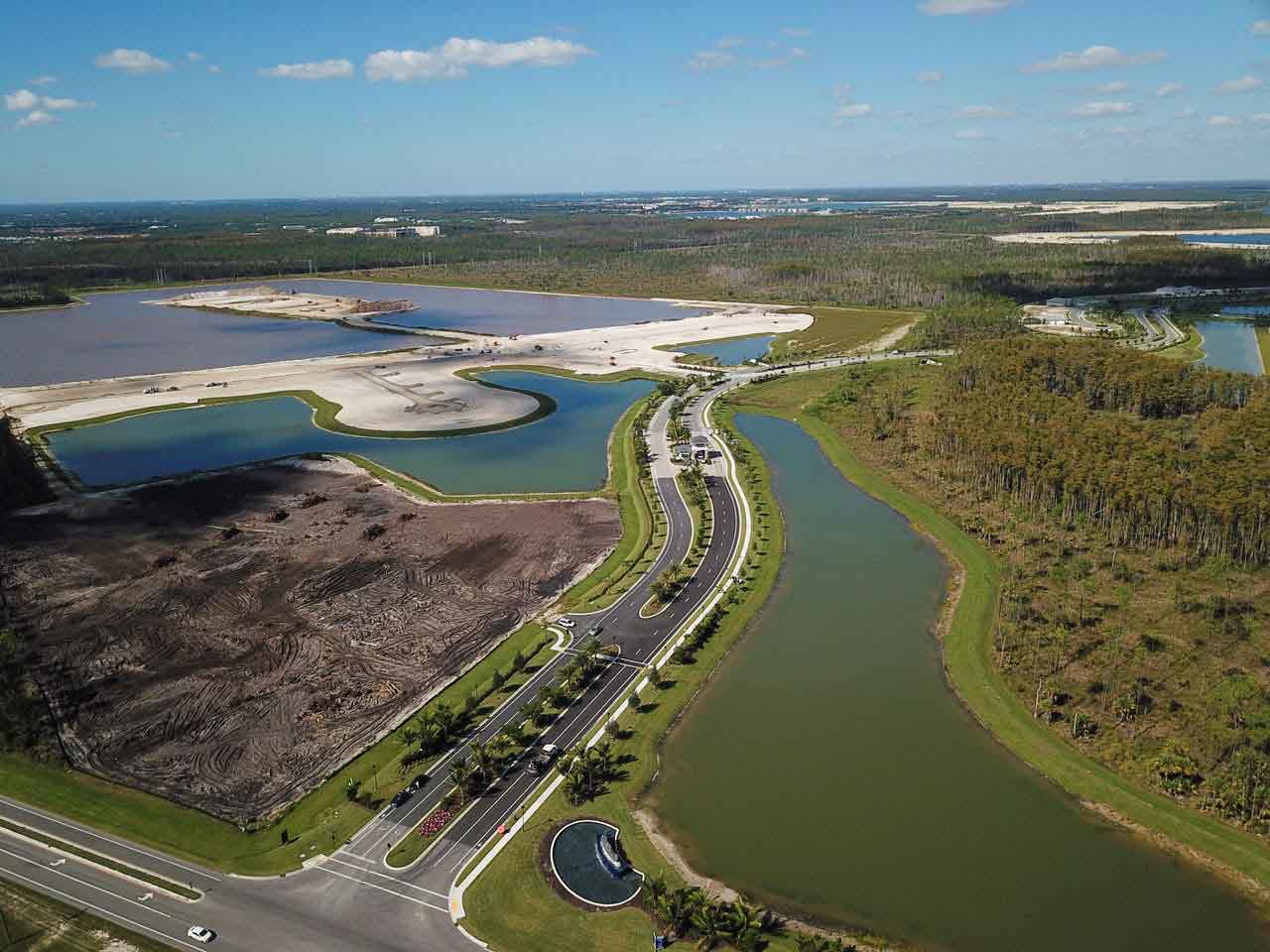 An aerial view of a lake surrounded by trees and a road.