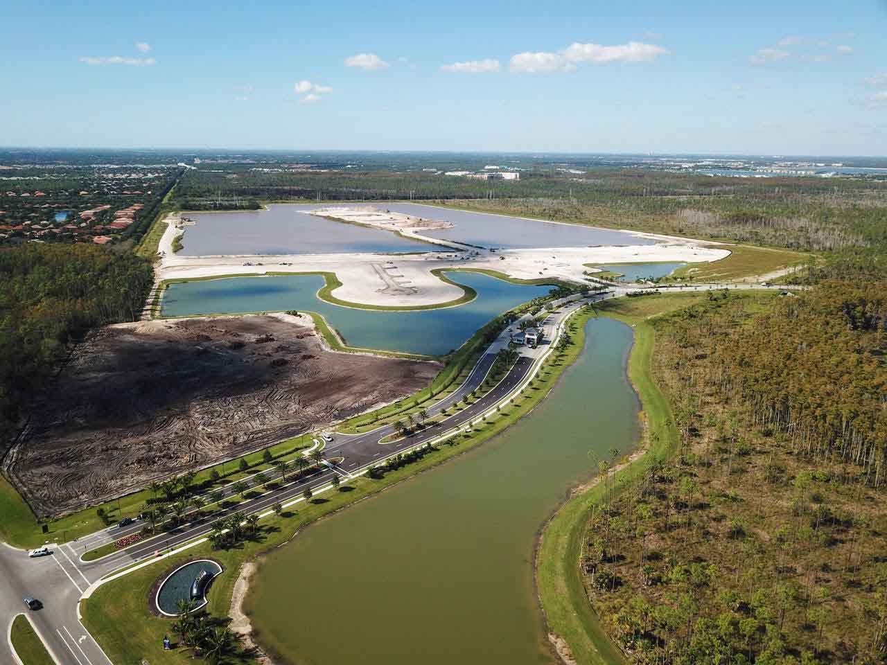 An aerial view of a lake surrounded by trees and a road.