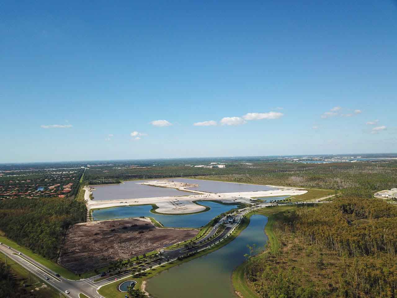 An aerial view of a lake surrounded by trees and a road.