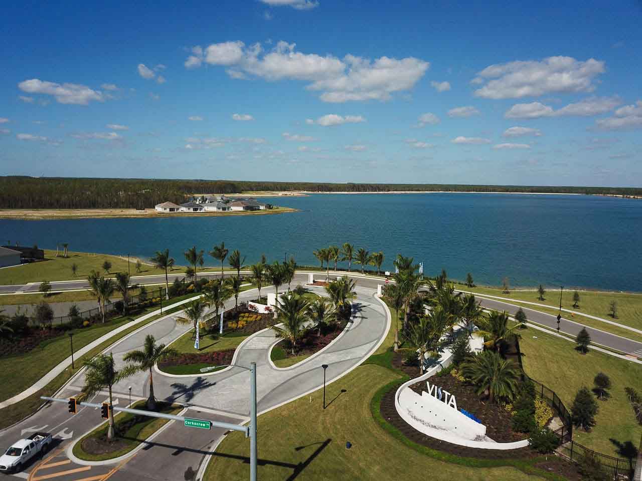 An aerial view of a lake with palm trees and a road