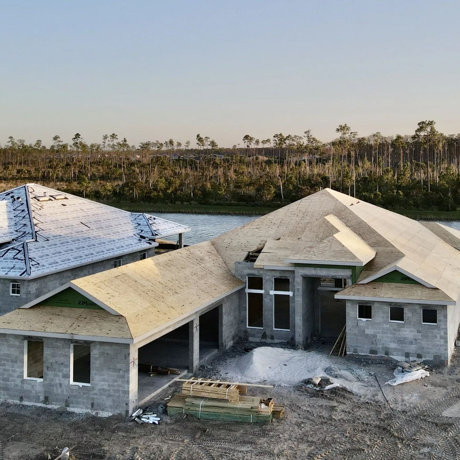 An aerial view of a house under construction with a lake in the background