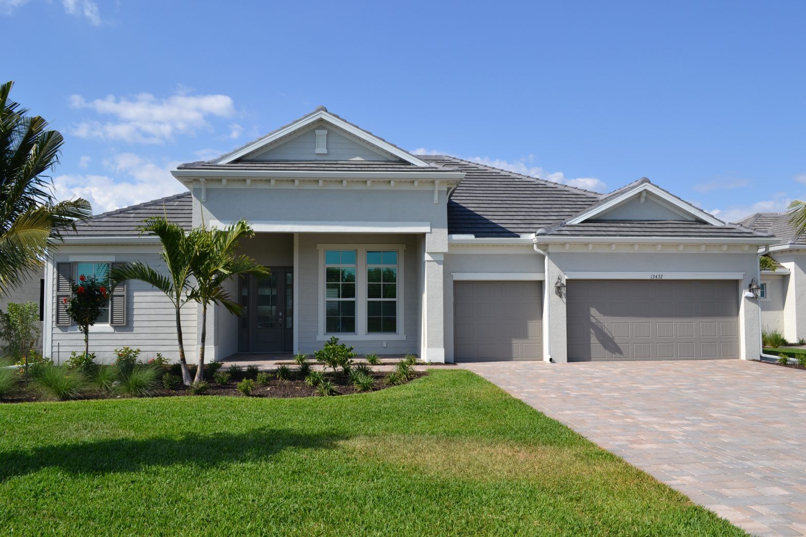 A large white house with two garages and a lush green lawn.