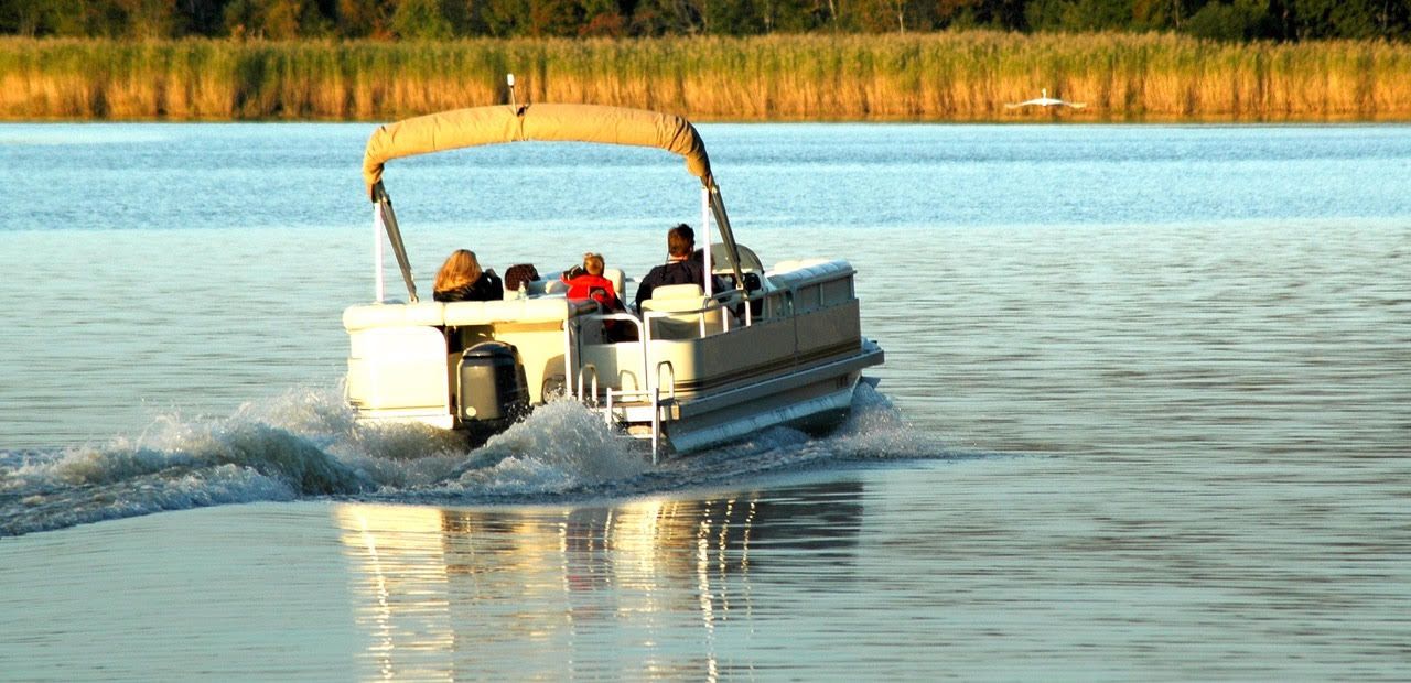 A pontoon boat is floating on top of a lake.