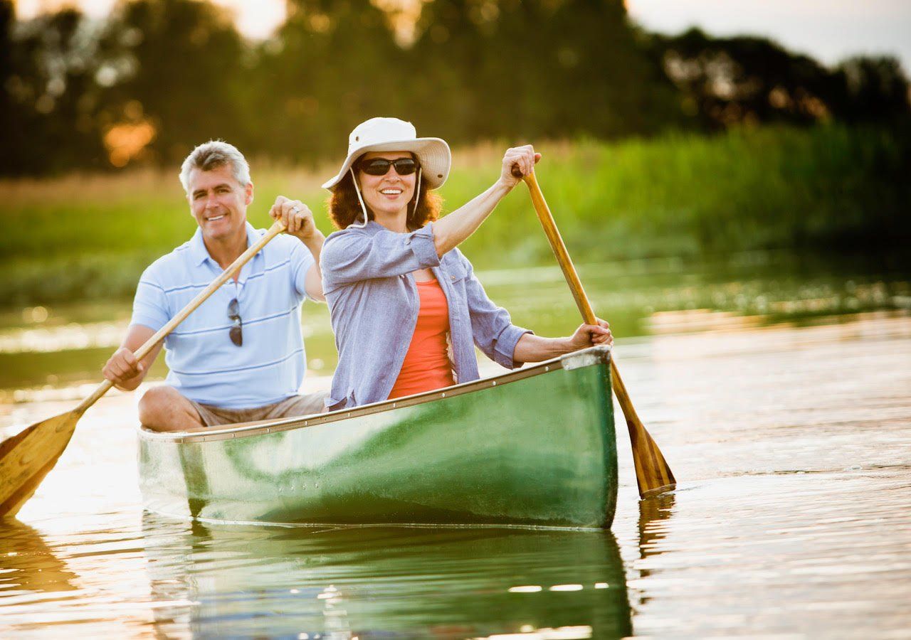A man and a woman are paddling a canoe on a river.