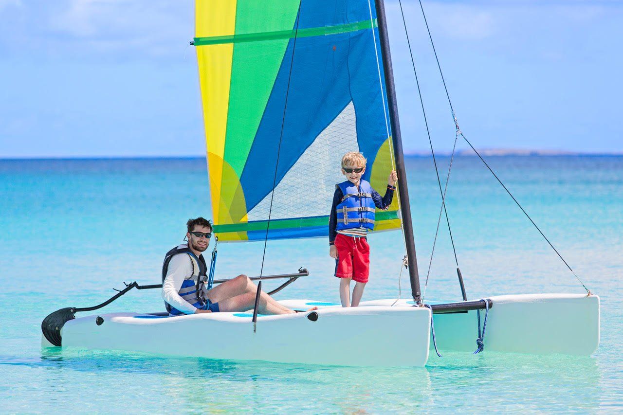 A man and a boy are sailing a sailboat in the ocean.