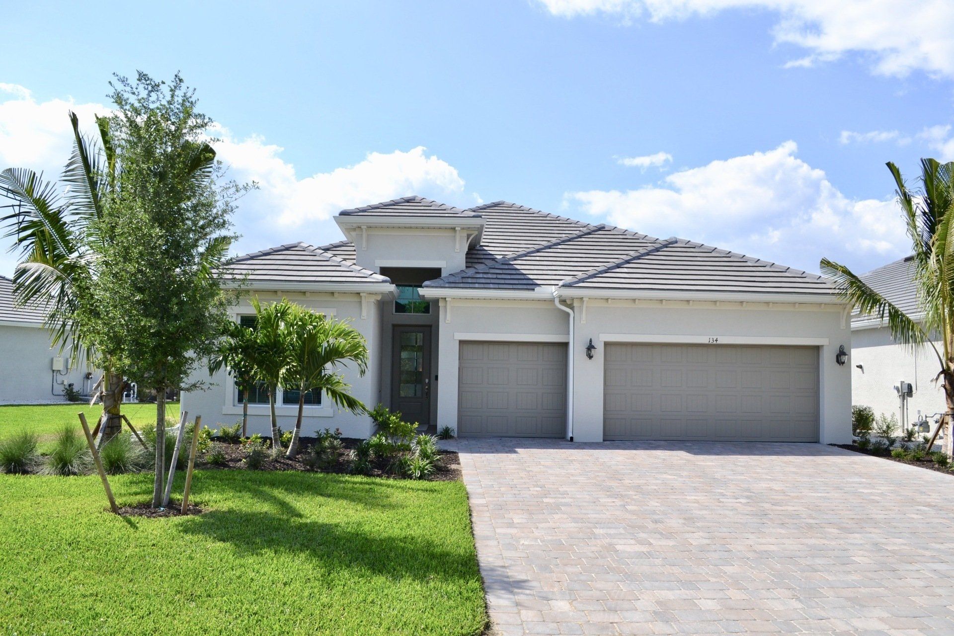 A white house with two garage doors and a driveway