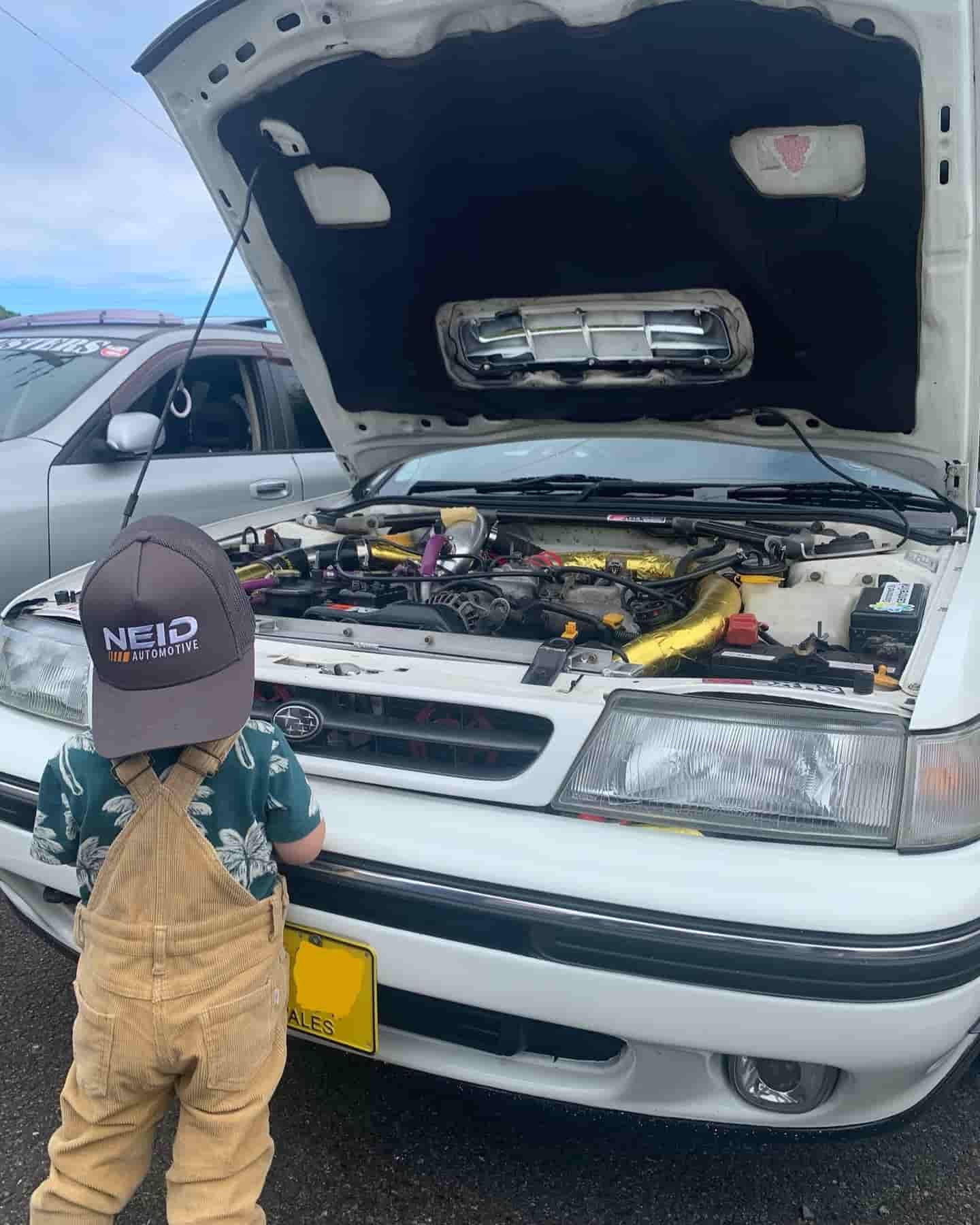 A Little Boy Is Looking Under The Hood Of A White Car — NEID Automotive In North Gosford, NSW