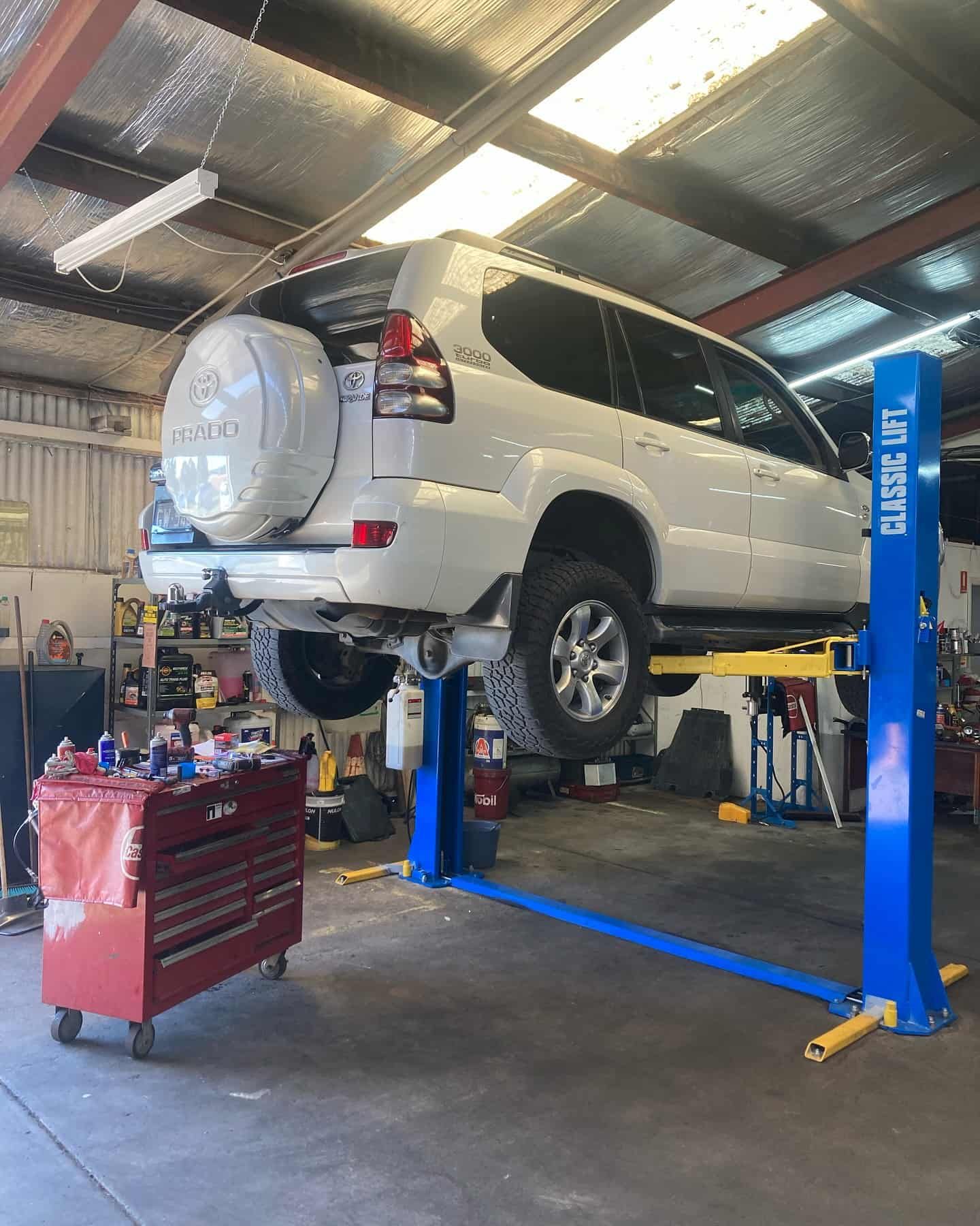 A White SUV Is Sitting On A Lift In A Garage — NEID Automotive In North Gosford, NSW