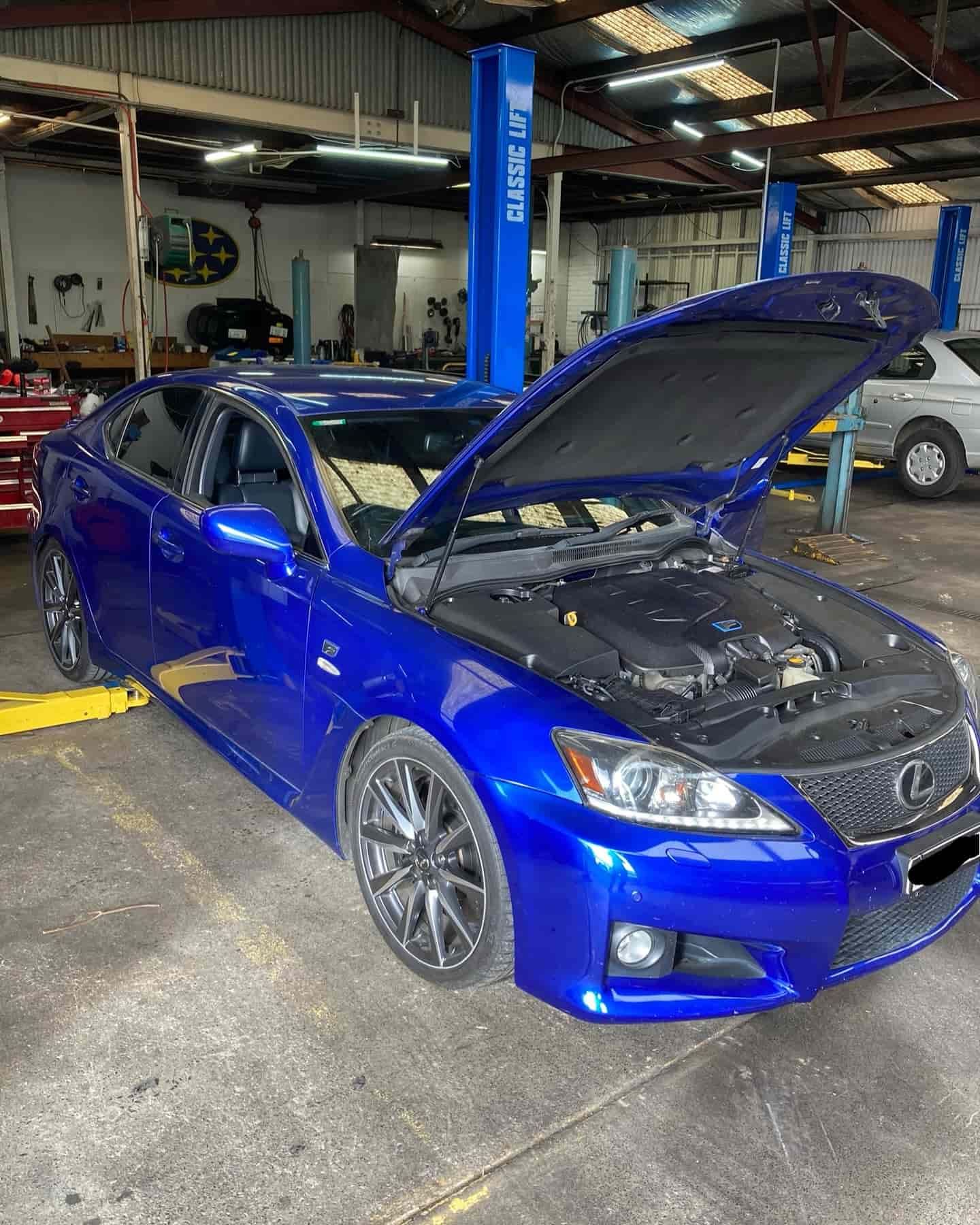 A White Car Is Sitting On A Lift In A Garage — NEID Automotive In North Gosford, NSW