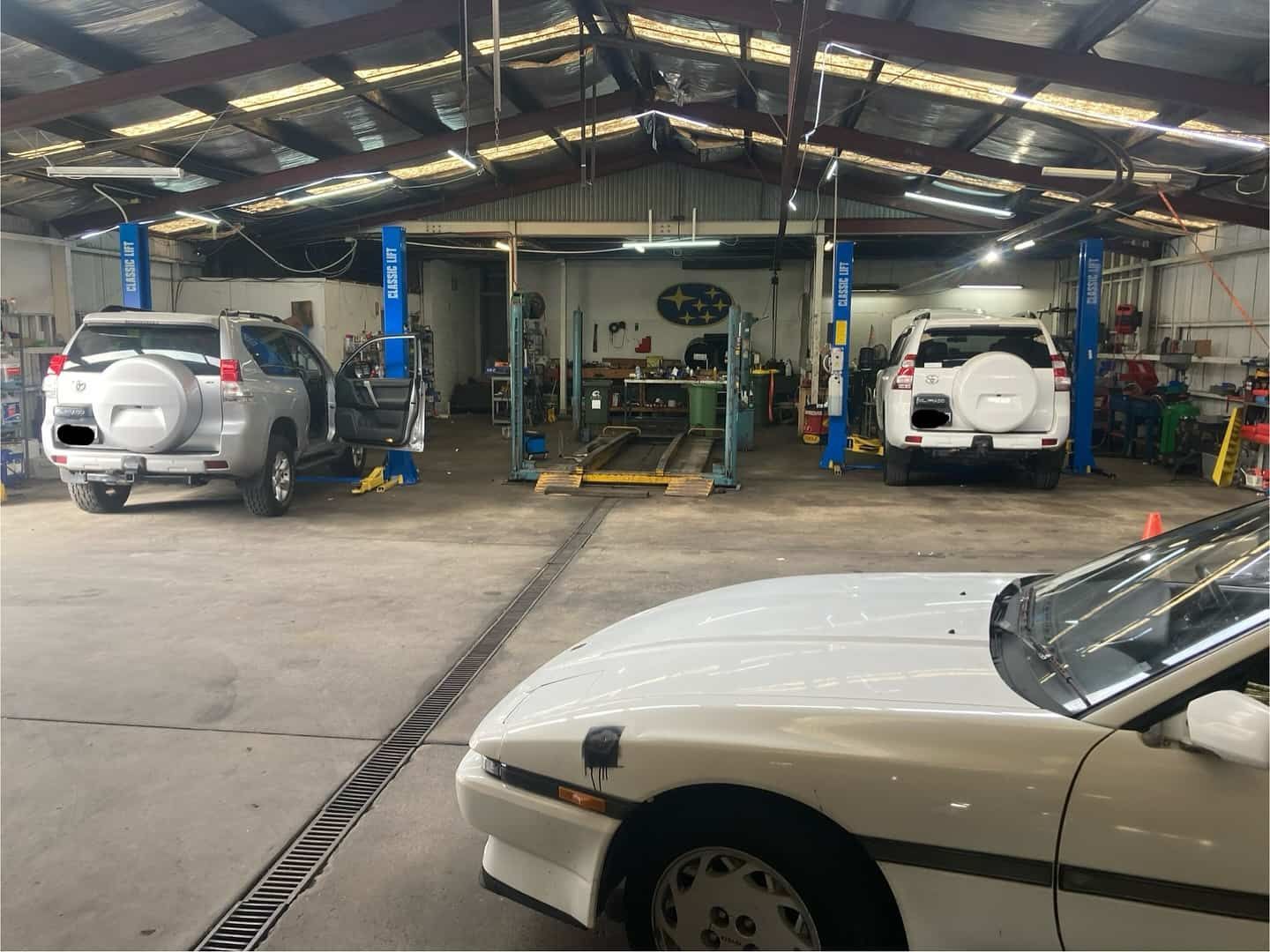 A White Car Is Parked In A Garage Next To A White SUV — NEID Automotive In North Gosford, NSW