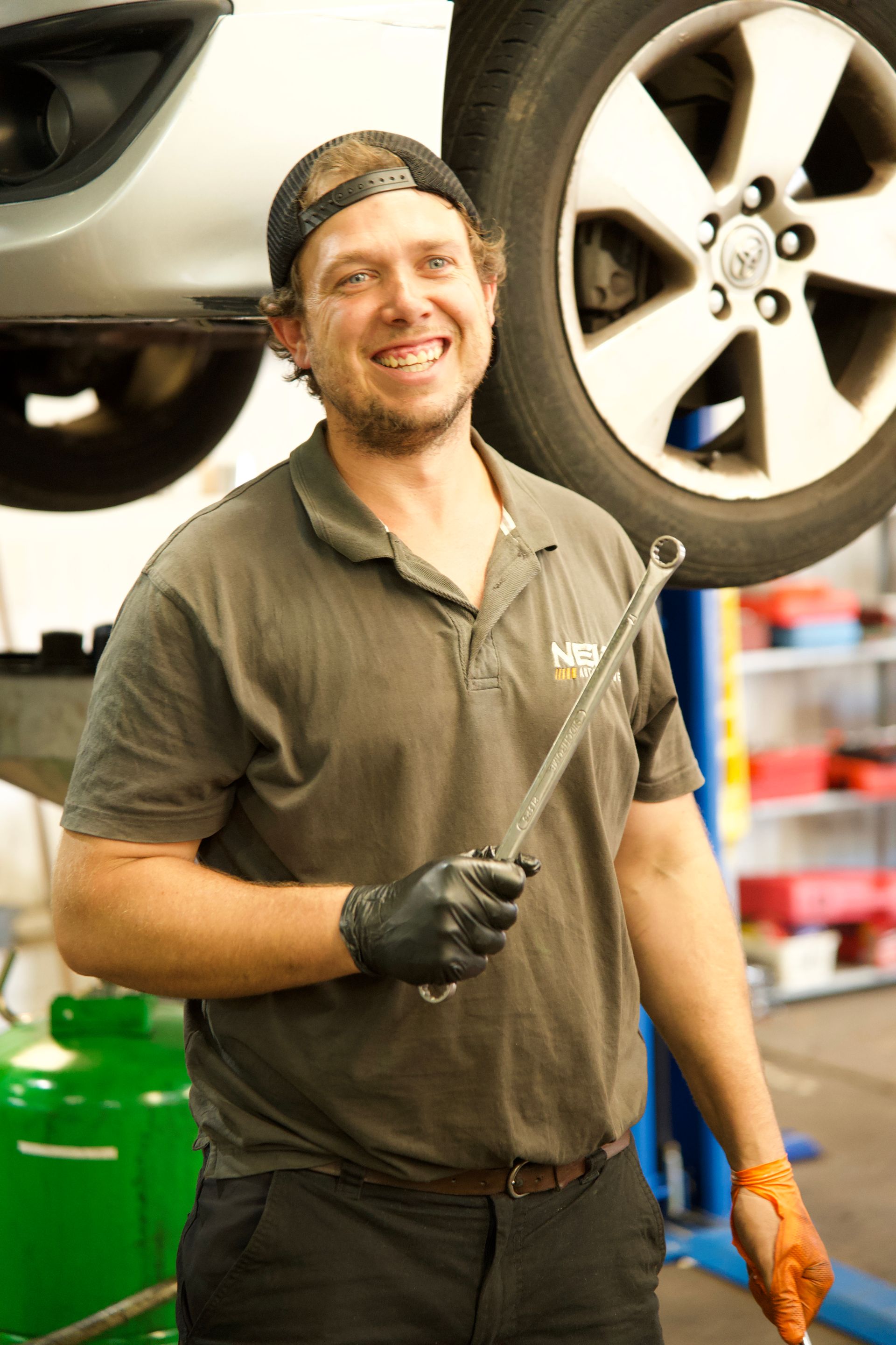 A Man Holding A Spanner In Front Of A Tyre Of A Car On A Wrench — NEID Automotive In North Gosford, NSW