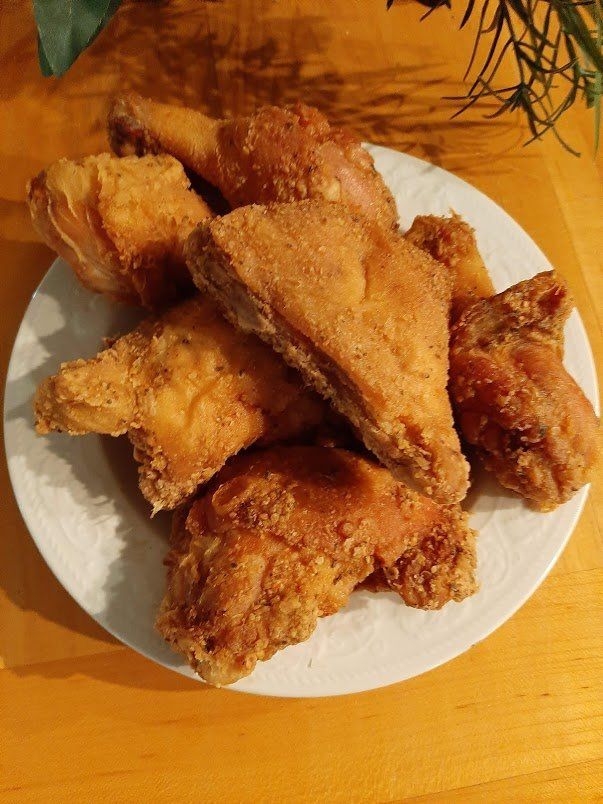 A white plate topped with fried chicken on a wooden table.