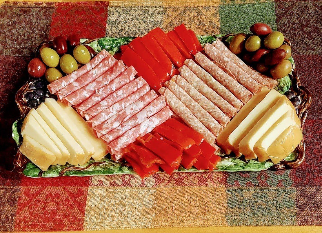 A tray of meats cheeses and olives on a table