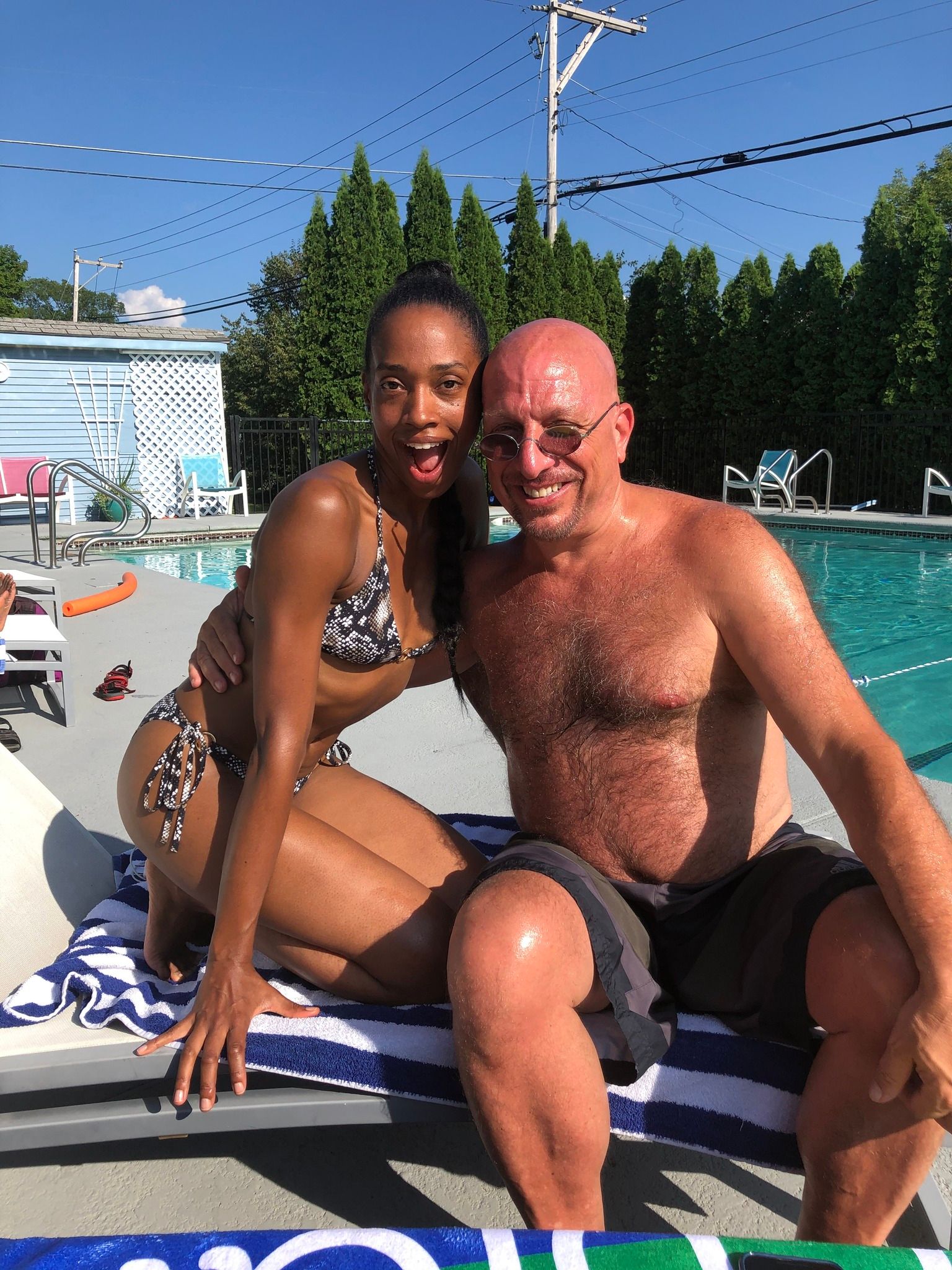 A man and a woman are posing for a picture in front of a swimming pool.