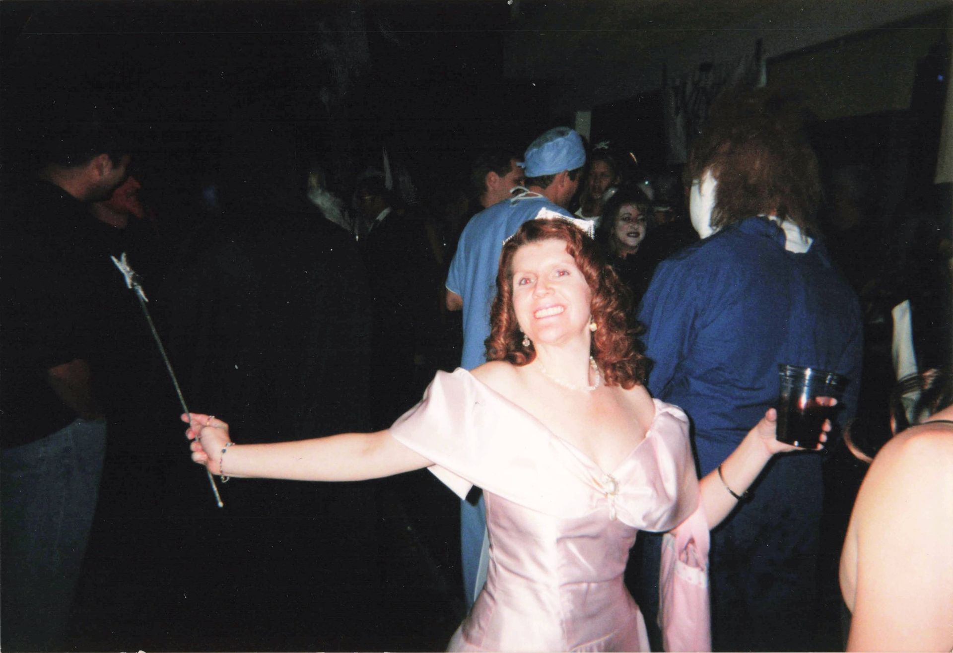 A woman in a pink dress is holding a wand
