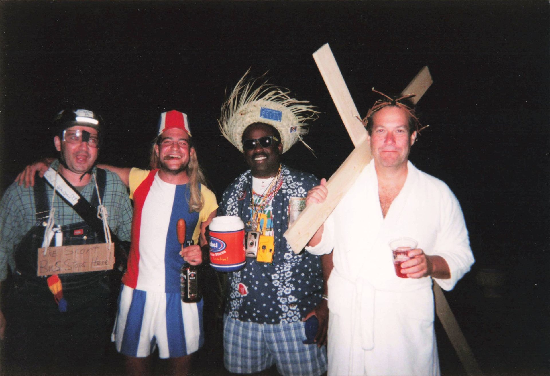 A group of men are posing for a picture and one of them is holding a wooden cross
