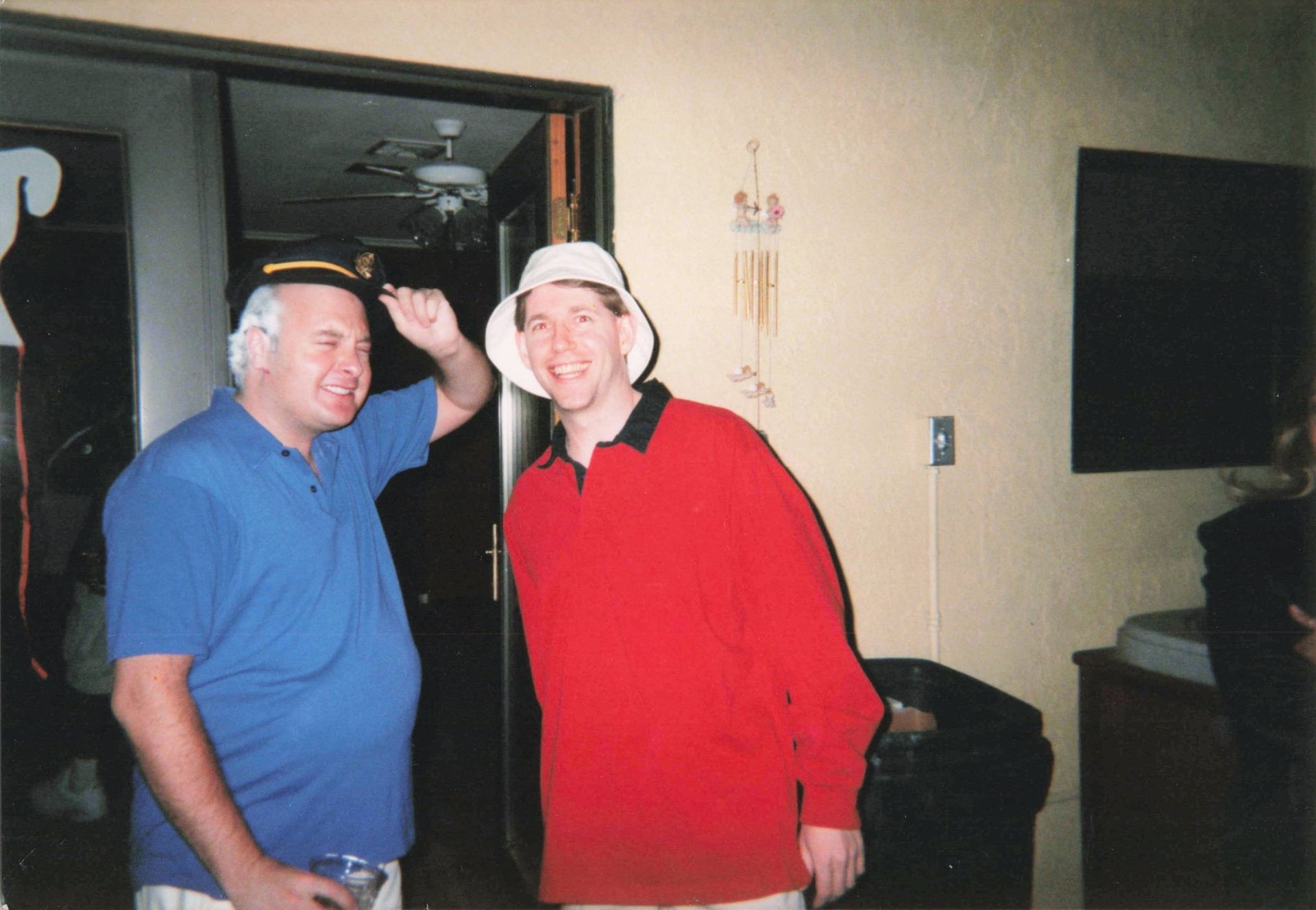 Two men standing next to each other one wearing a hat