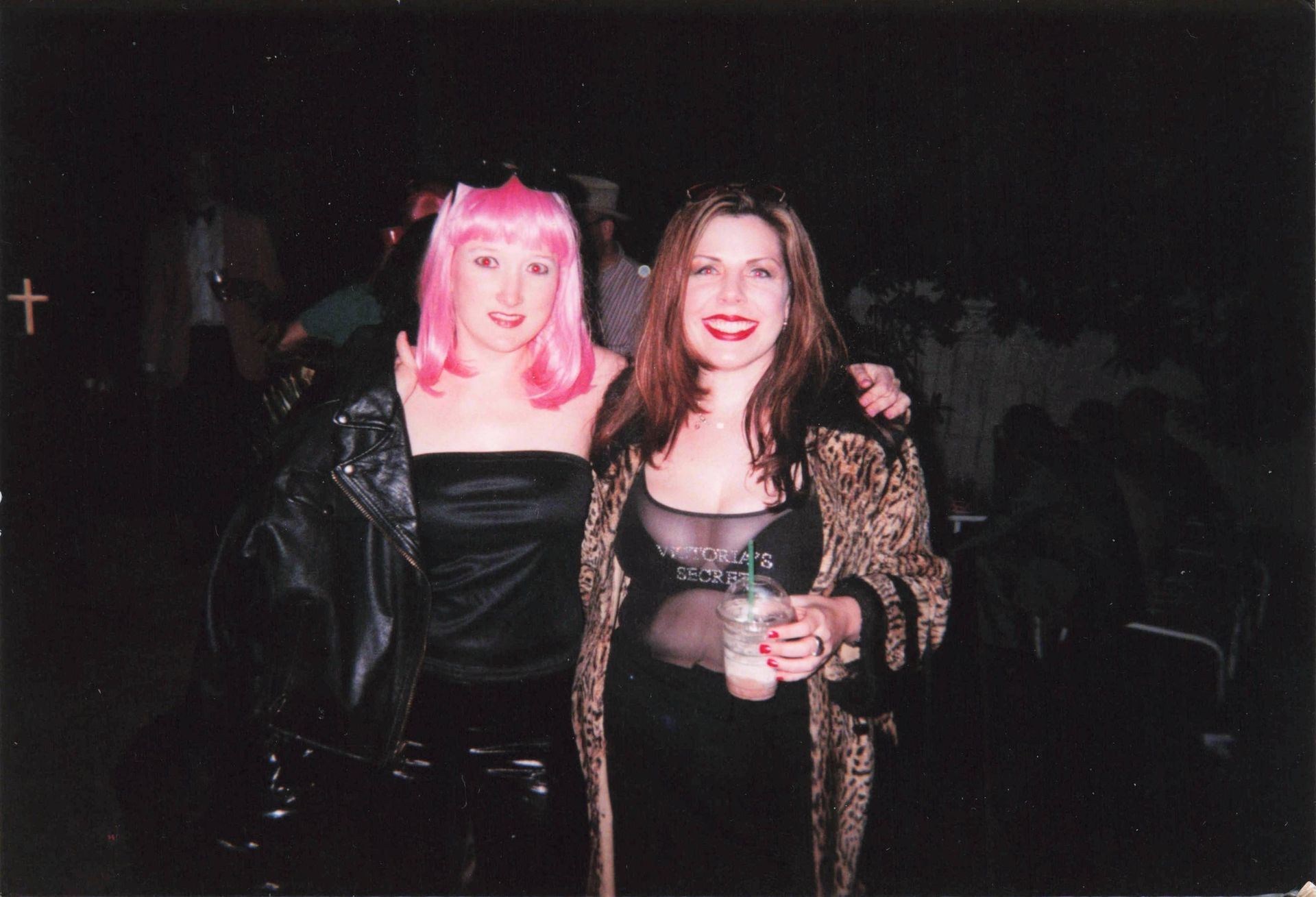 Two women posing for a picture with a cross in the background