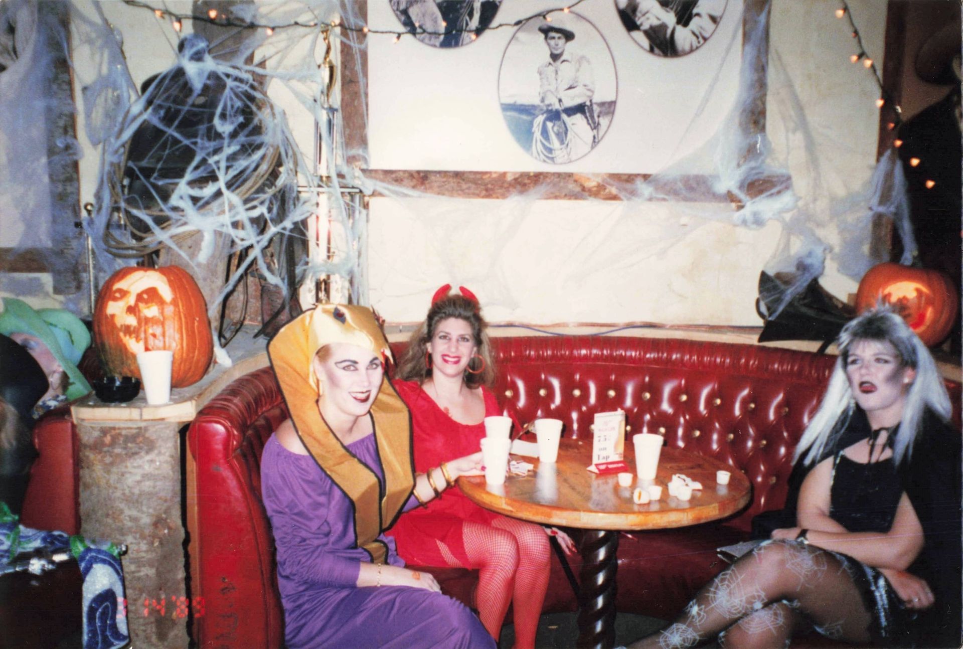 A group of women dressed in halloween costumes are sitting around a table