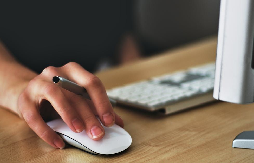 A person is using a computer mouse and writing on a keyboard.