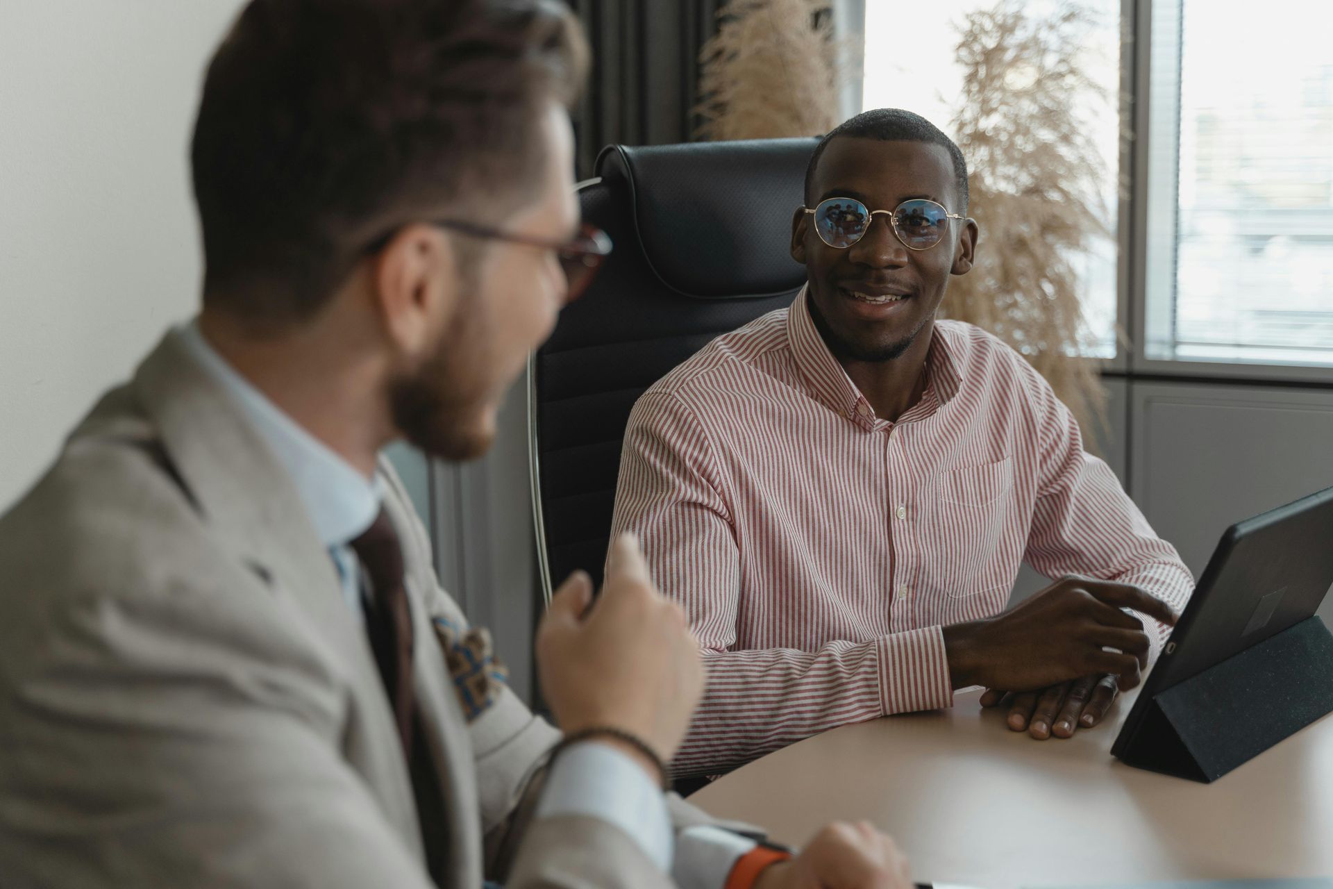 Two men are sitting at a table talking to each other.