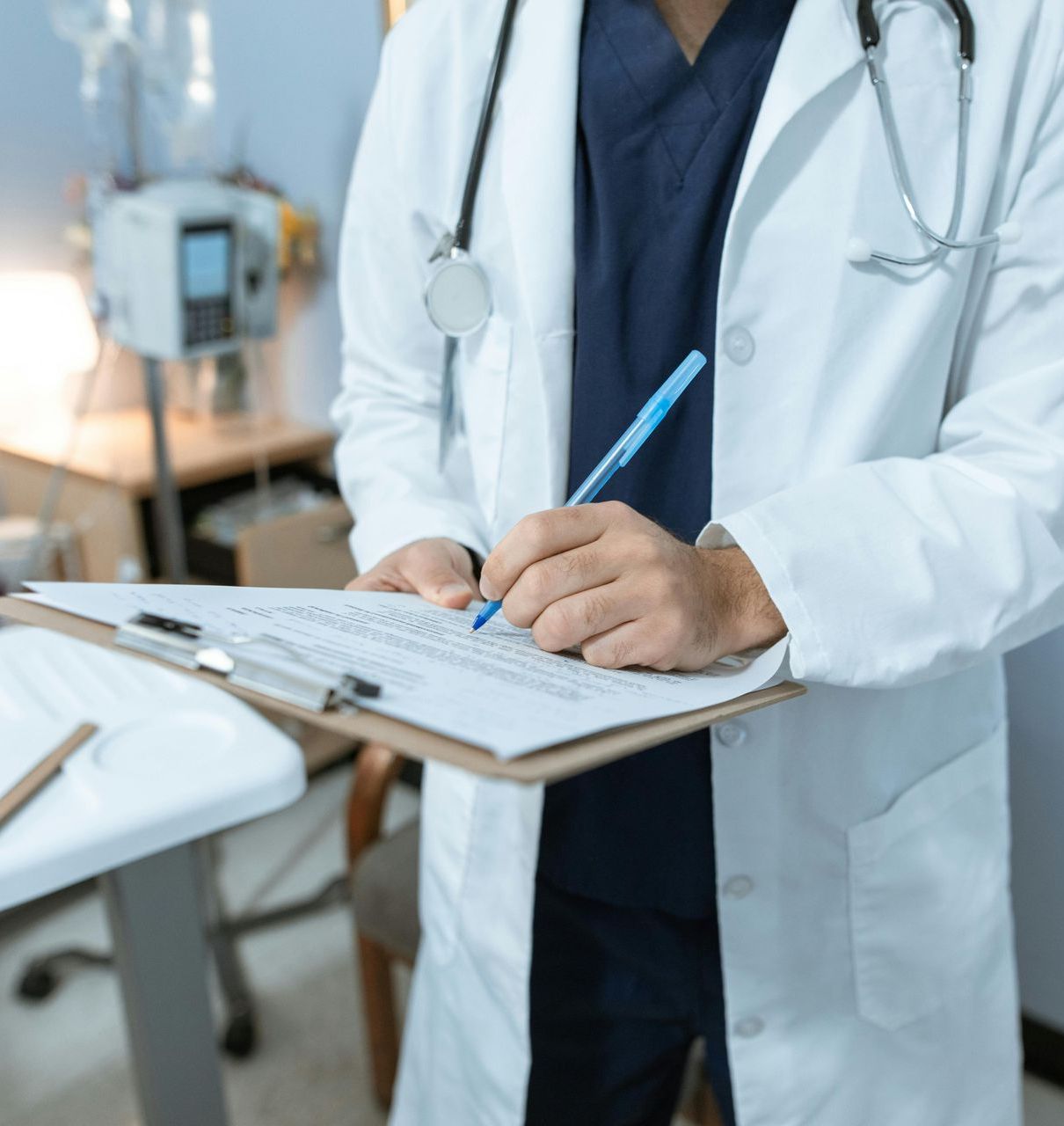 A doctor is writing on a clipboard with a pen.