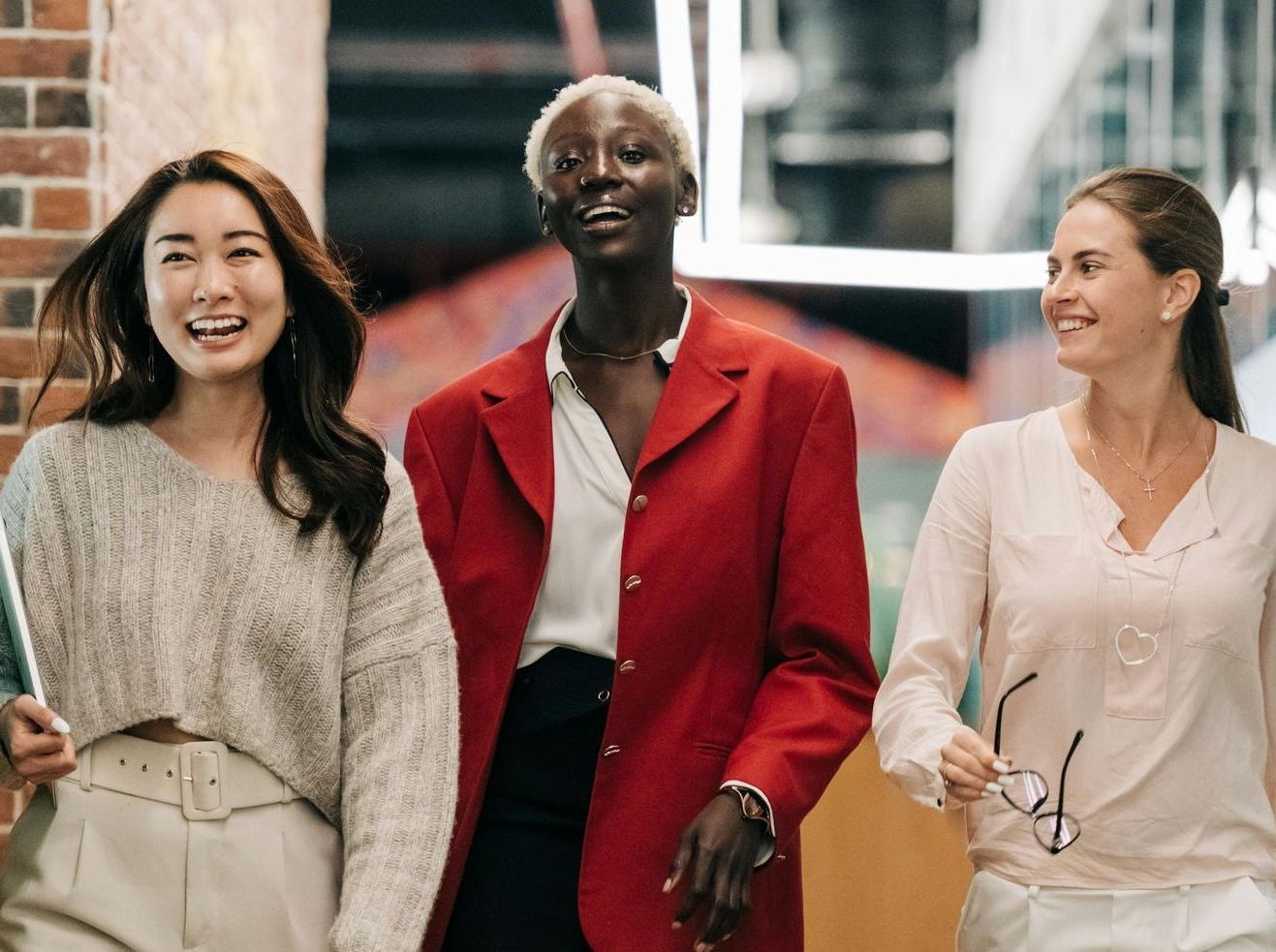 A group of three women are walking down a hallway.